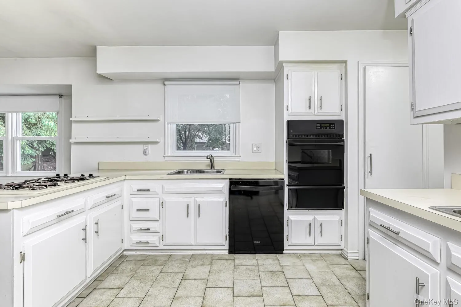 Kitchen with black appliances, a warming drawer, a sink, and light countertops Kitchen with black appliances, a warming drawer, a sink, and light countertops