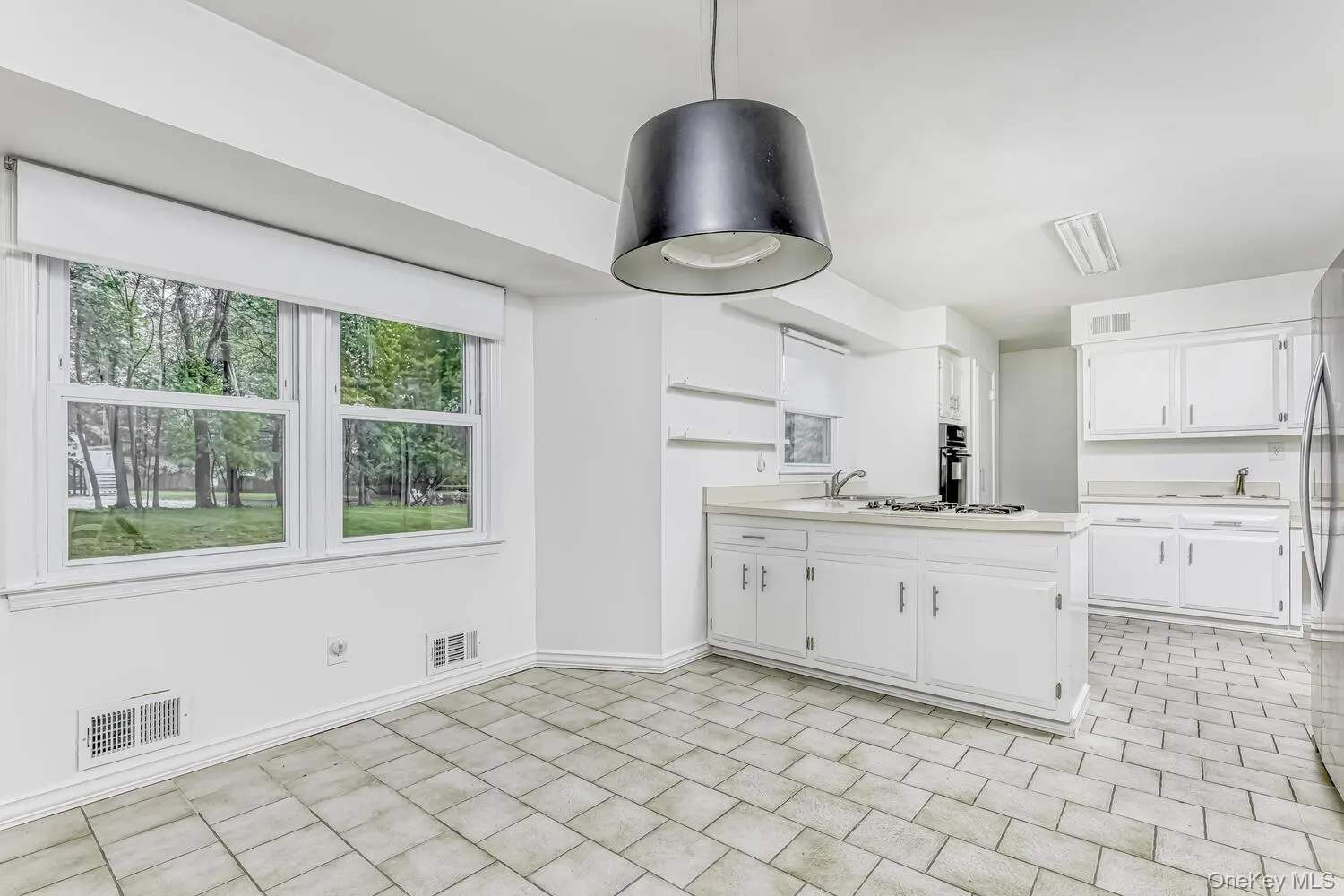 Kitchen featuring white cabinetry, light countertops, white gas cooktop, a peninsula, and baseboards Kitchen featuring white cabinetry, light countertops, white gas cooktop, a peninsula, and baseboards