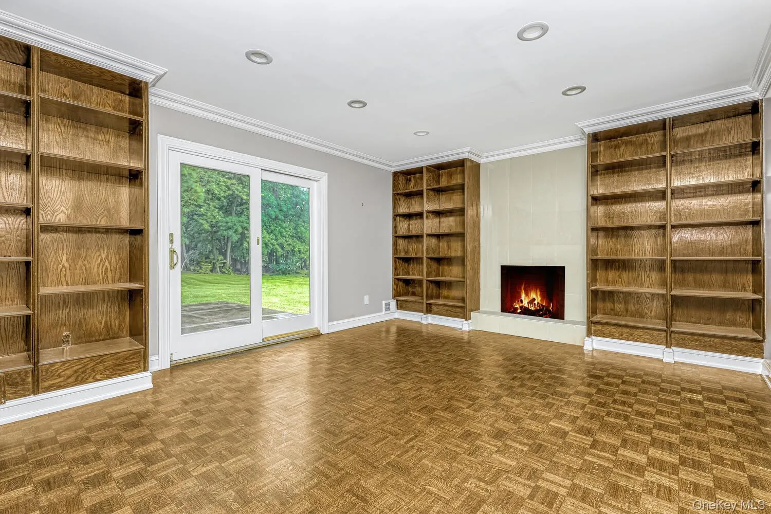 Unfurnished living room with built in shelves, a fireplace, baseboards, ornamental molding, and recessed lighting Unfurnished living room with built in shelves, a fireplace, baseboards, ornamental molding, and recessed lighting