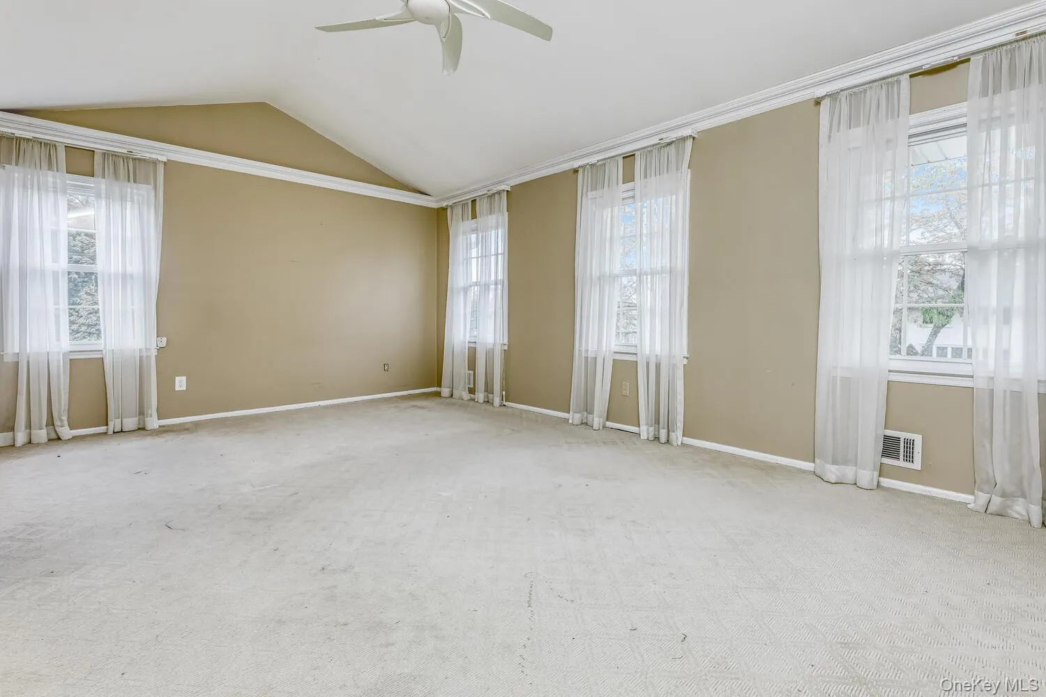 Unfurnished room featuring ceiling fan, plenty of natural light, lofted ceiling, and carpet floors Unfurnished room featuring ceiling fan, plenty of natural light, lofted ceiling, and carpet floors