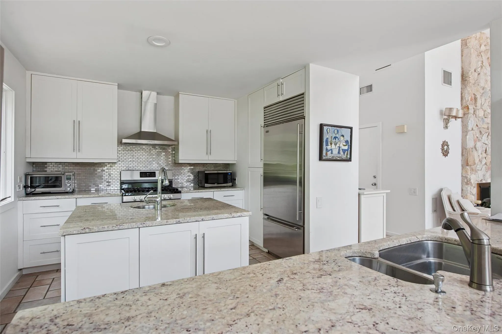Kitchen with wall chimney exhaust hood, stainless steel appliances, light stone counters, and a sink Kitchen with wall chimney exhaust hood, stainless steel appliances, light stone counters, and a sink