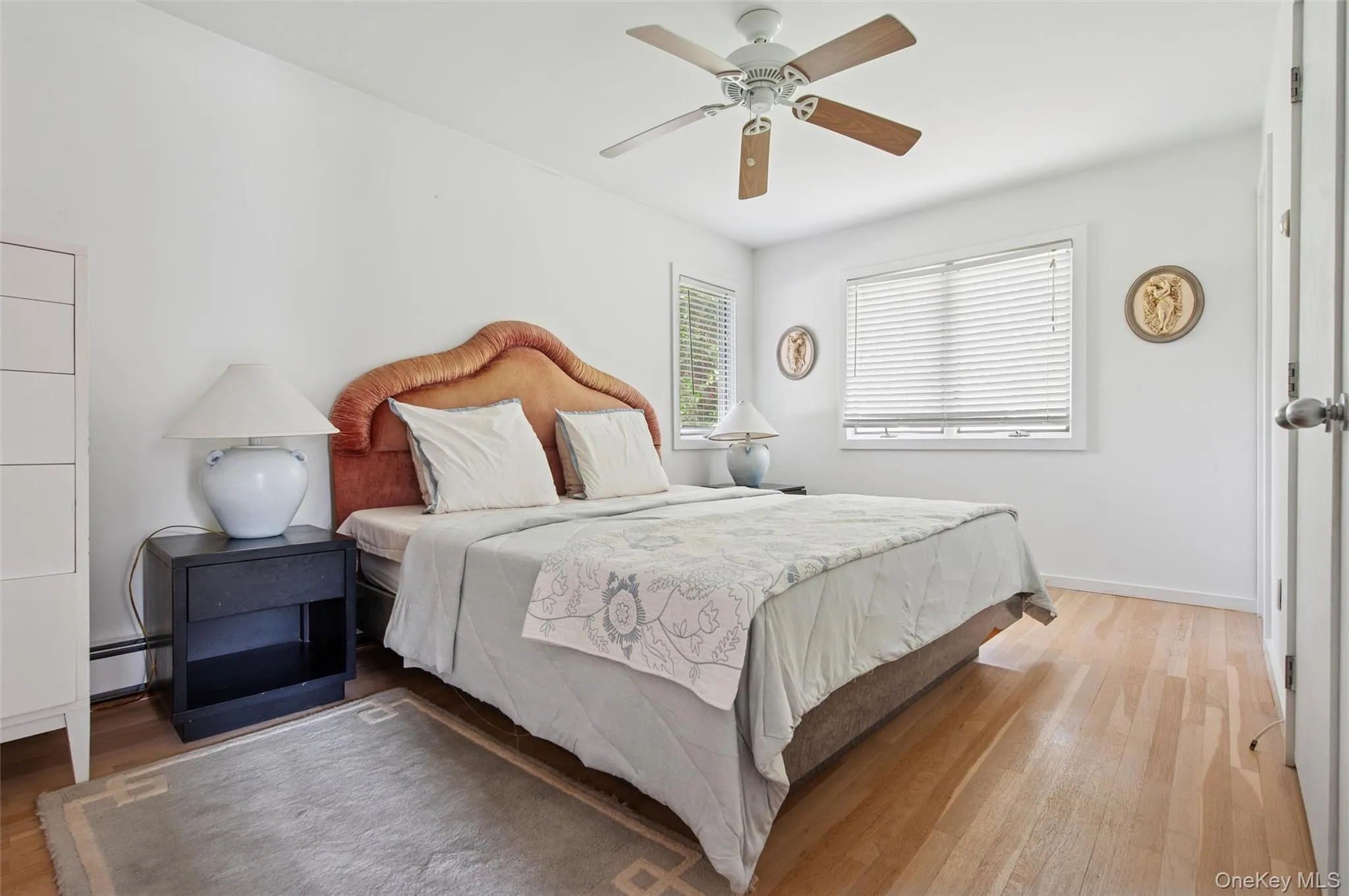 Bedroom featuring wood finished floors, a baseboard radiator, baseboards, and ceiling fan Bedroom featuring wood finished floors, a baseboard radiator, baseboards, and ceiling fan