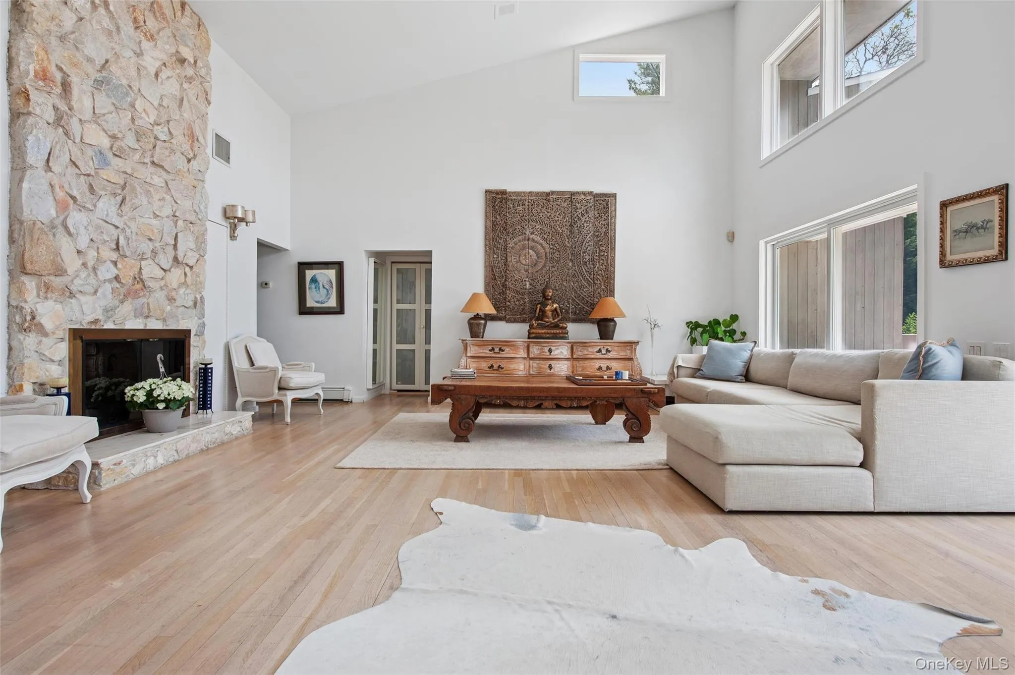 Living area featuring high vaulted ceiling, wood finished floors, and a fireplace Living area featuring high vaulted ceiling, wood finished floors, and a fireplace