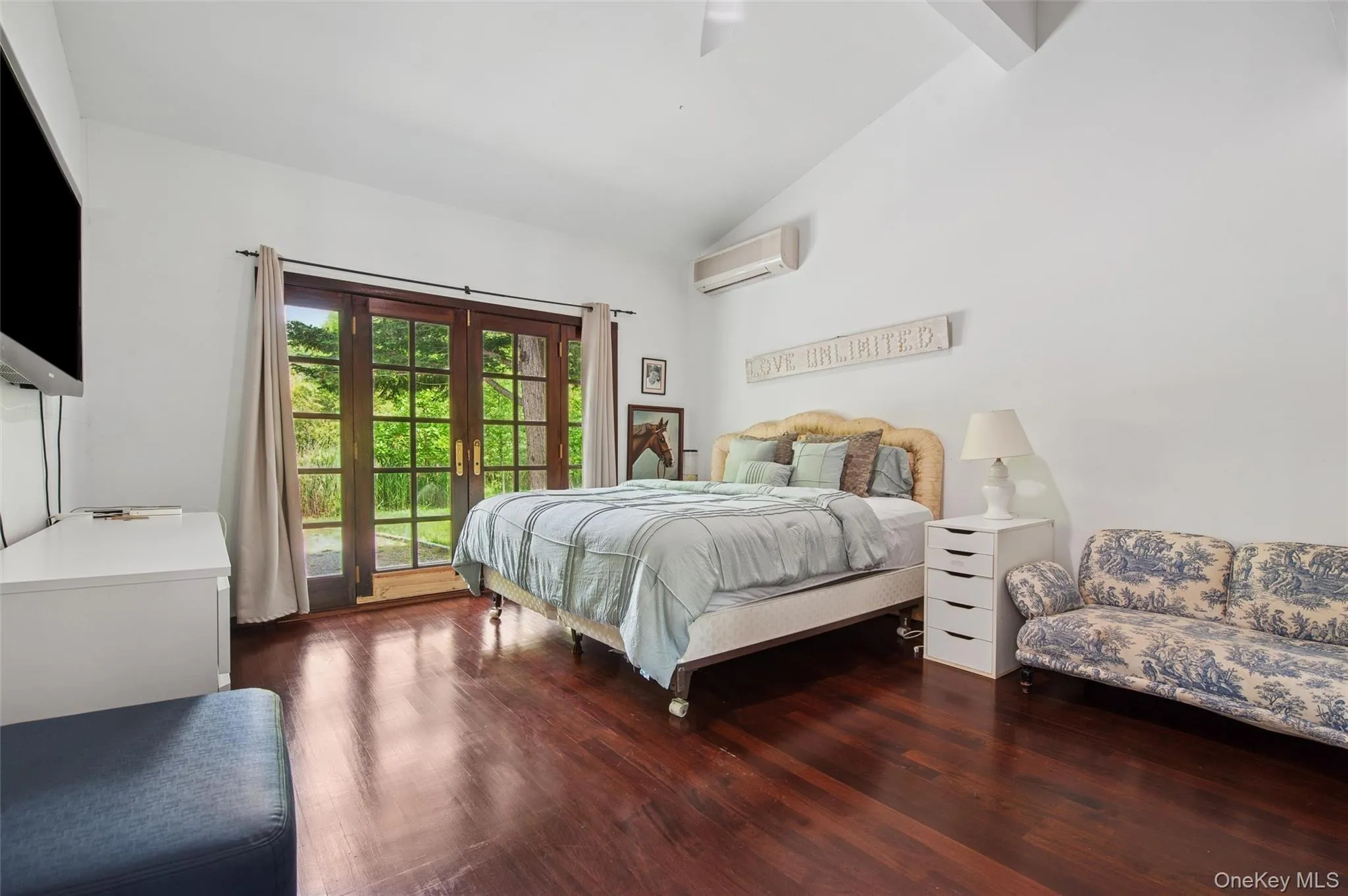 Bedroom with access to outside, a wall mounted air conditioner, wood finished floors, and high vaulted ceiling Bedroom with access to outside, a wall mounted air conditioner, wood finished floors, and high vaulted ceiling