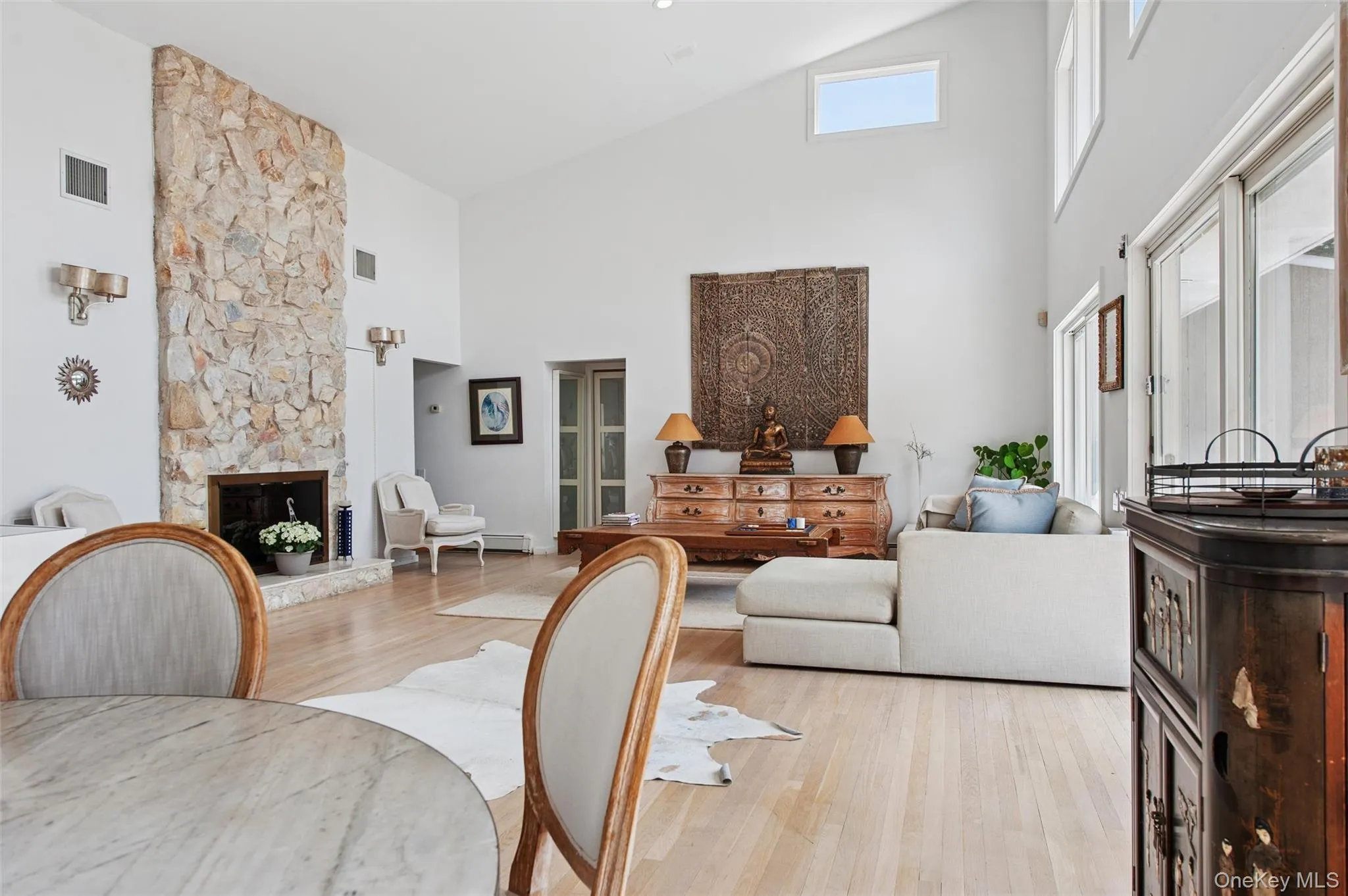 Living area with high vaulted ceiling, wood finished floors, and a stone fireplace Living area with high vaulted ceiling, wood finished floors, and a stone fireplace