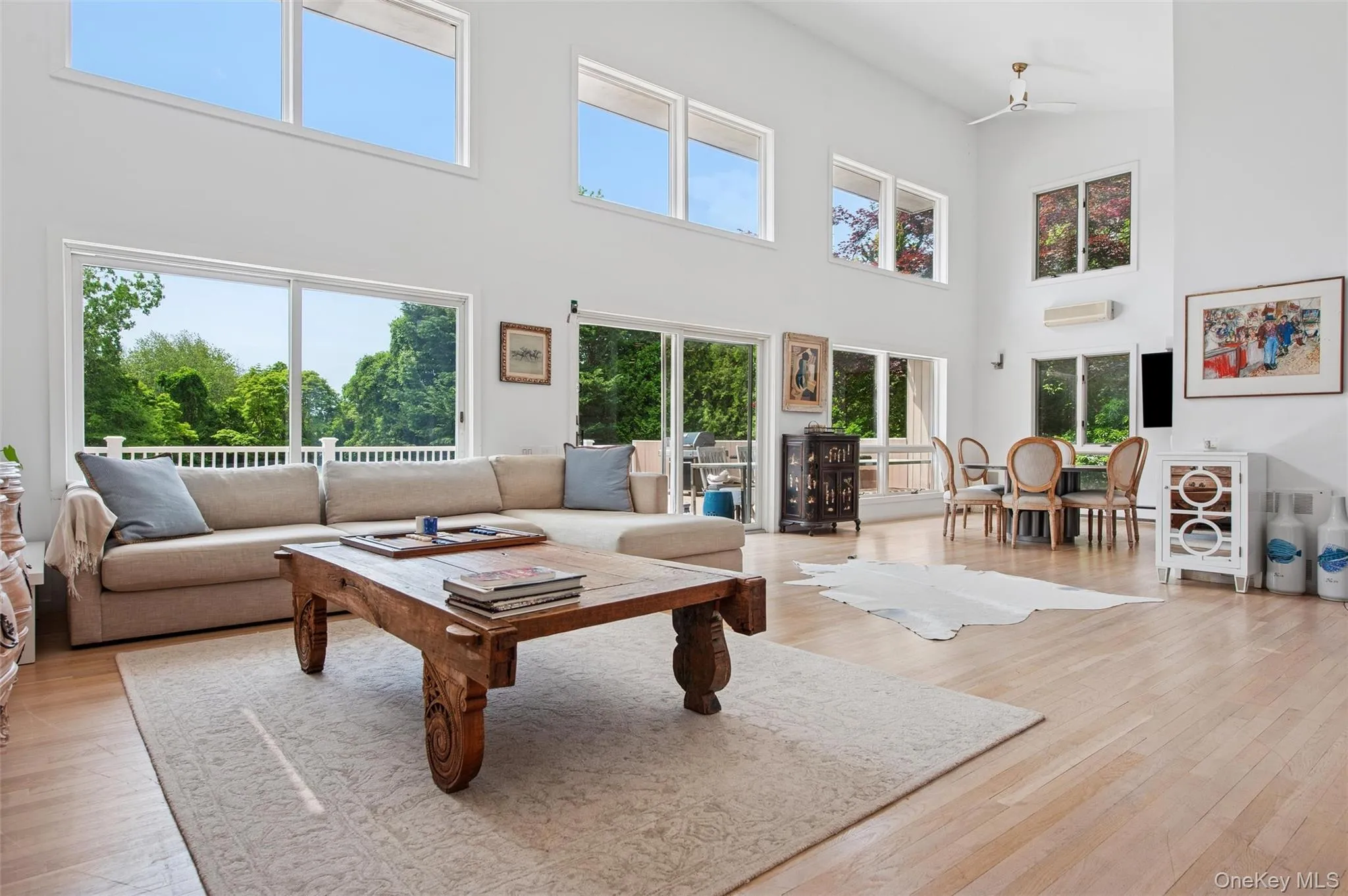 Living room featuring a high ceiling, light wood-type flooring, and a wall mounted air conditioner Living room featuring a high ceiling, light wood-type flooring, and a wall mounted air conditioner