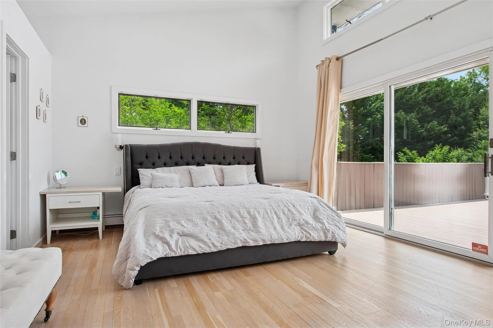 Bedroom featuring access to outside, wood finished floors, a high ceiling, and a baseboard heating unit Bedroom featuring access to outside, wood finished floors, a high ceiling, and a baseboard heating unit