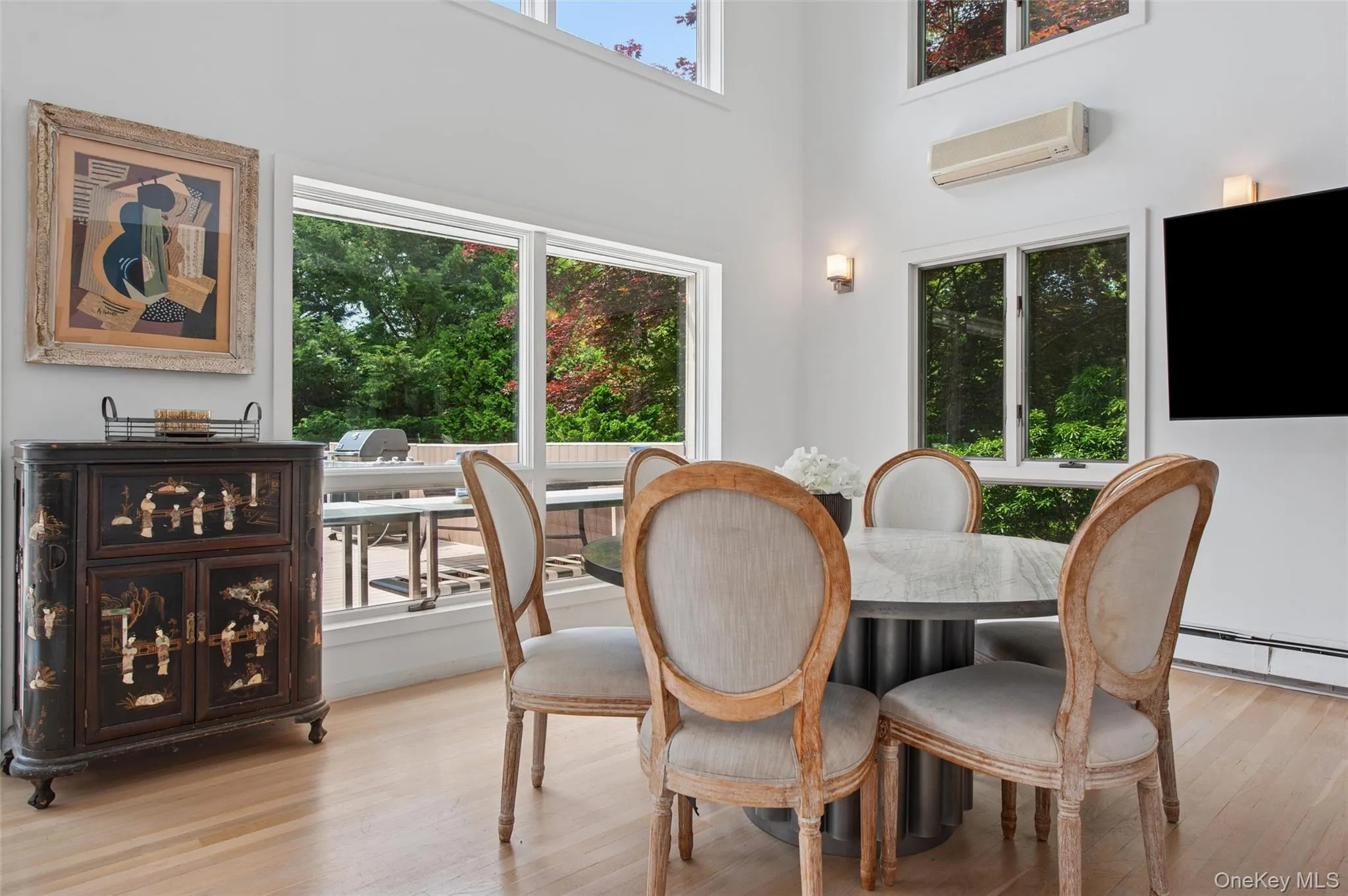 Dining room with a wall unit AC, wood finished floors, a high ceiling, and a baseboard radiator Dining room with a wall unit AC, wood finished floors, a high ceiling, and a baseboard radiator