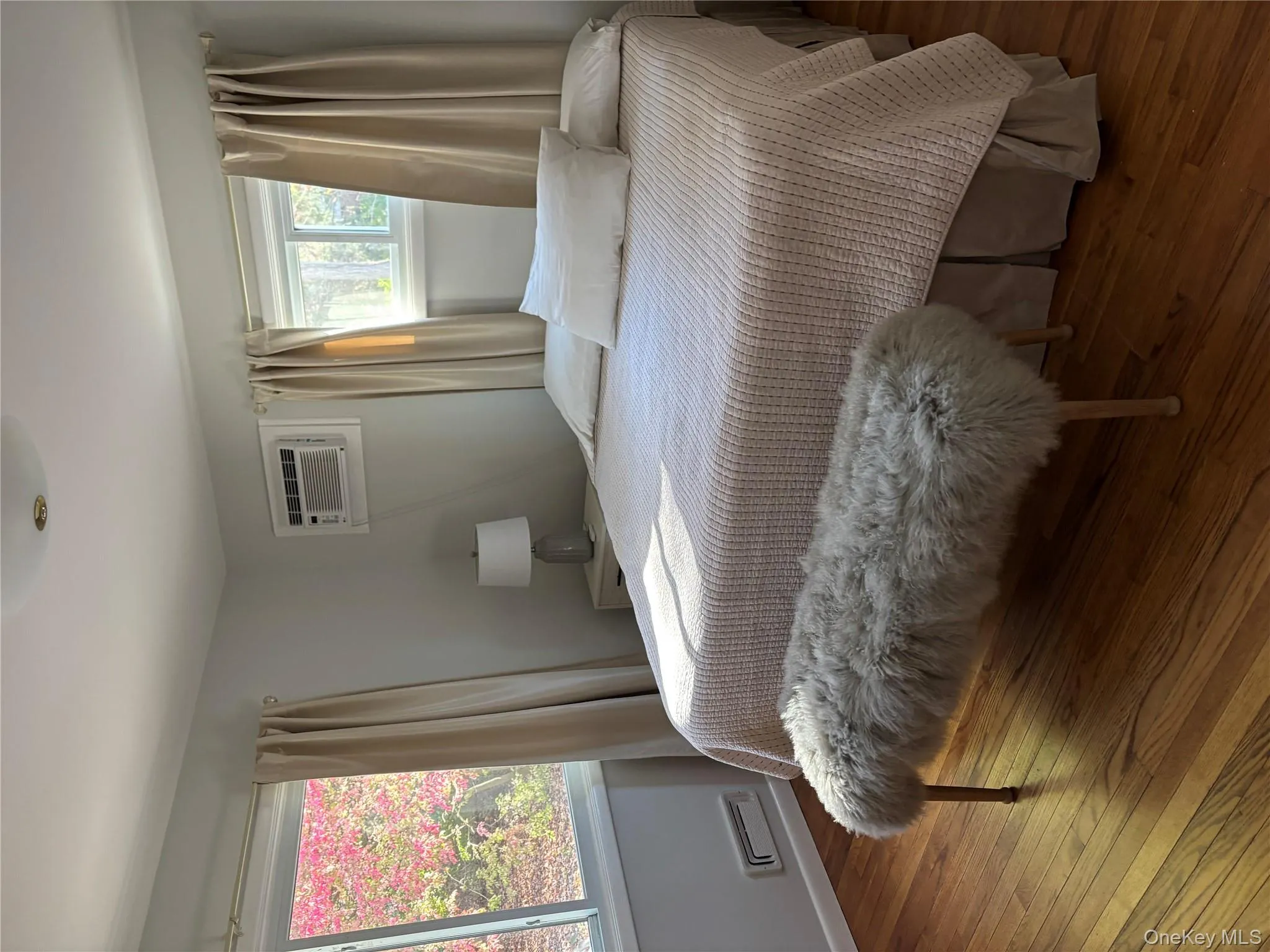 Bedroom with wood-type flooring and an AC wall unit Bedroom with wood-type flooring and an AC wall unit
