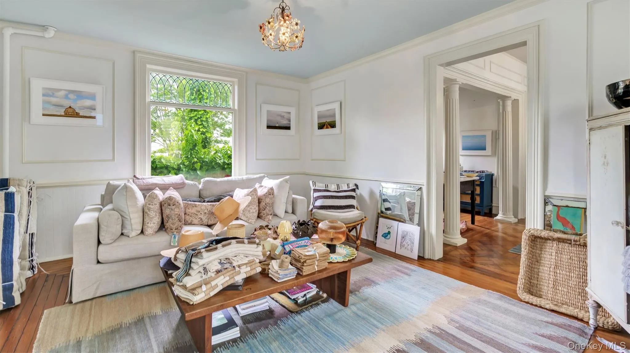 Living room with a chandelier, wood finished floors, and ornate columns Living room with a chandelier, wood finished floors, and ornate columns