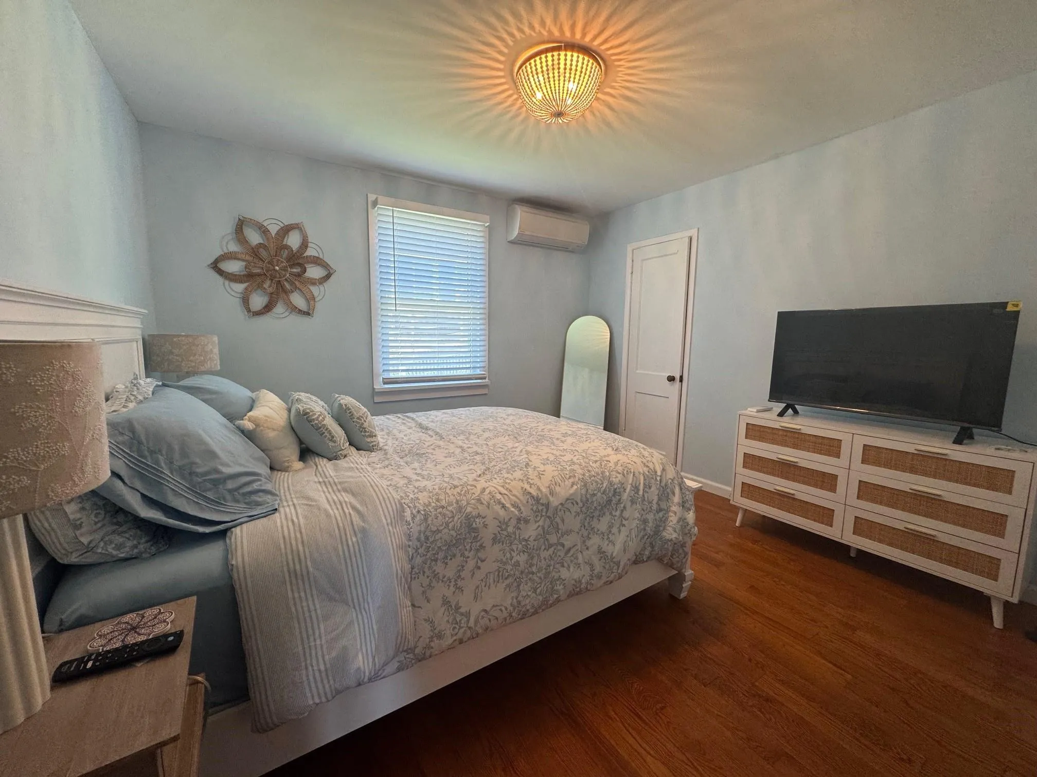 Bedroom with an AC wall unit, wood finished floors, and baseboards Bedroom with an AC wall unit, wood finished floors, and baseboards