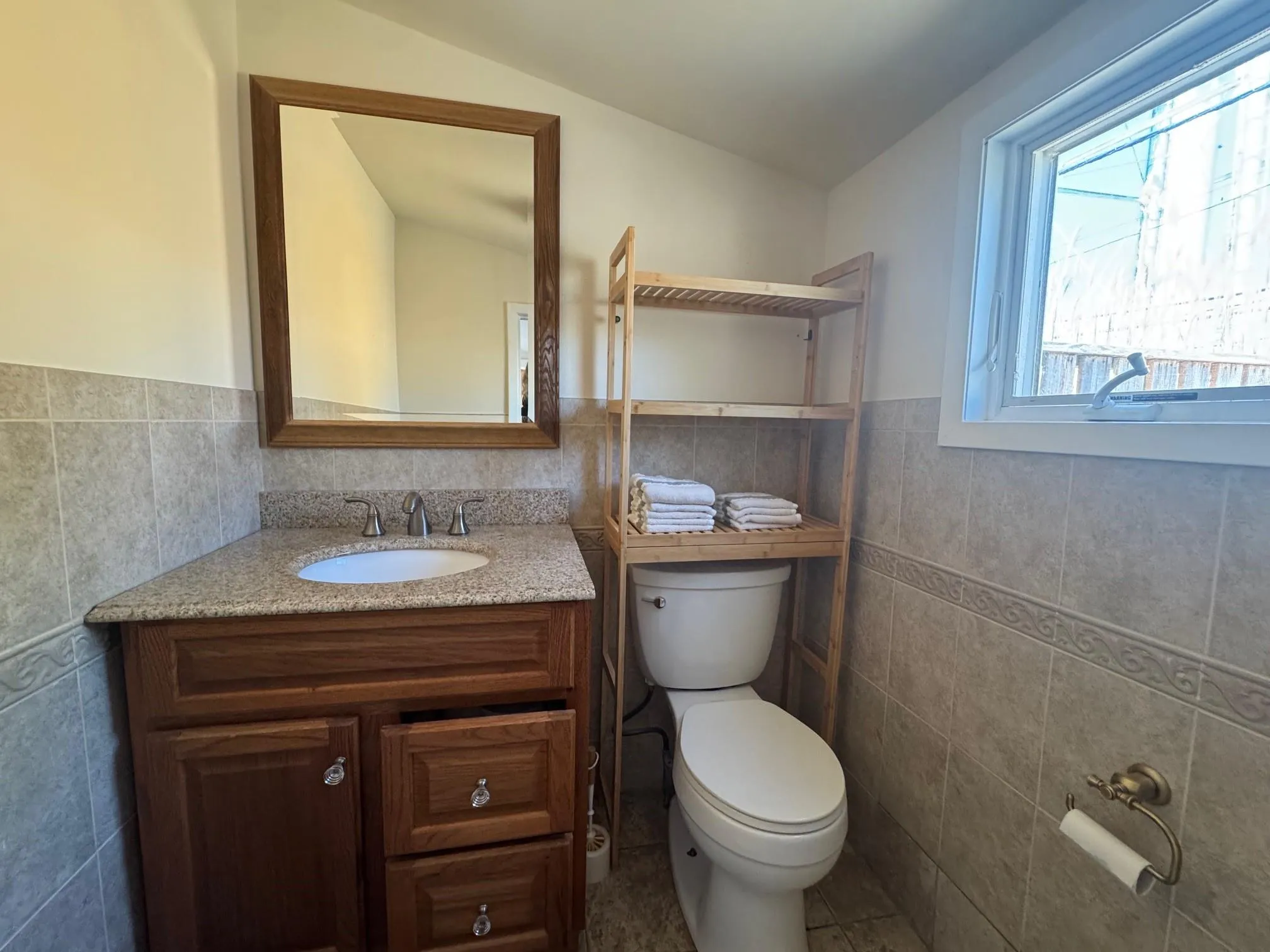 Half bath featuring tile walls, toilet, vanity, a wainscoted wall, and tile patterned floors Half bath featuring tile walls, toilet, vanity, a wainscoted wall, and tile patterned floors