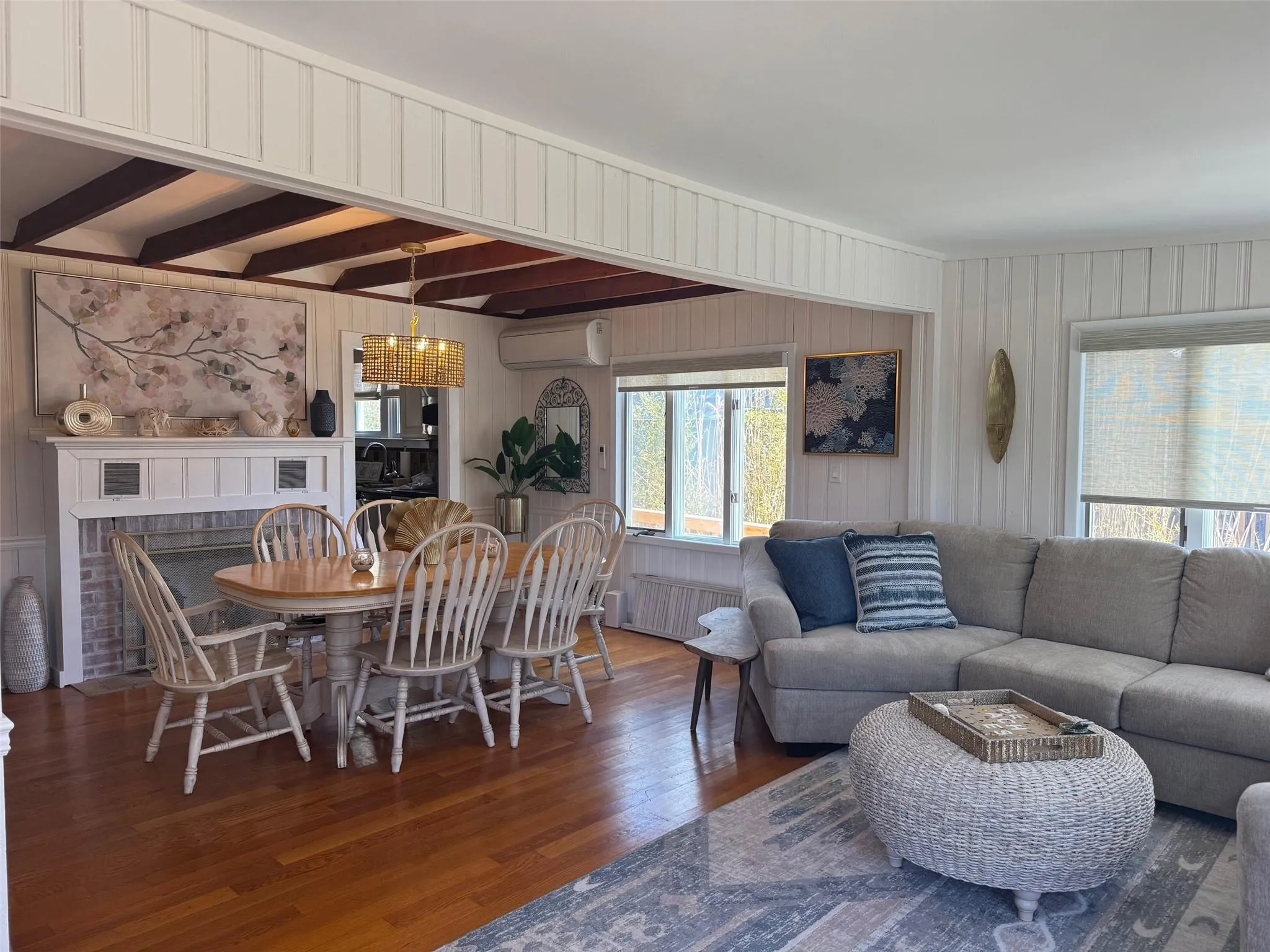 Dining space with a wall unit AC, radiator, wood finished floors, a chandelier, and a brick fireplace Dining space with a wall unit AC, radiator, wood finished floors, a chandelier, and a brick fireplace