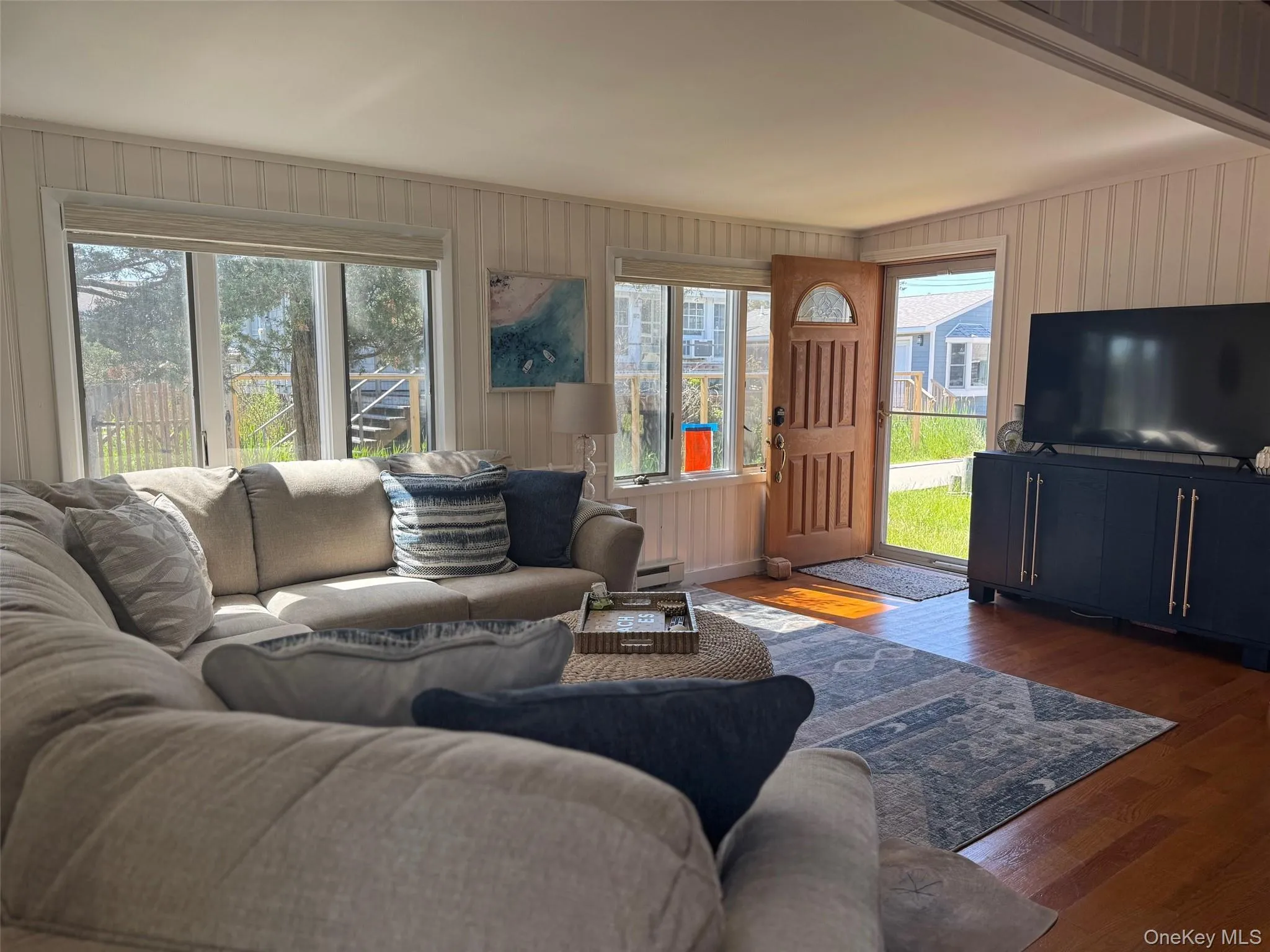Living area featuring plenty of natural light, baseboard heating, wood finished floors, and wood walls Living area featuring plenty of natural light, baseboard heating, wood finished floors, and wood walls