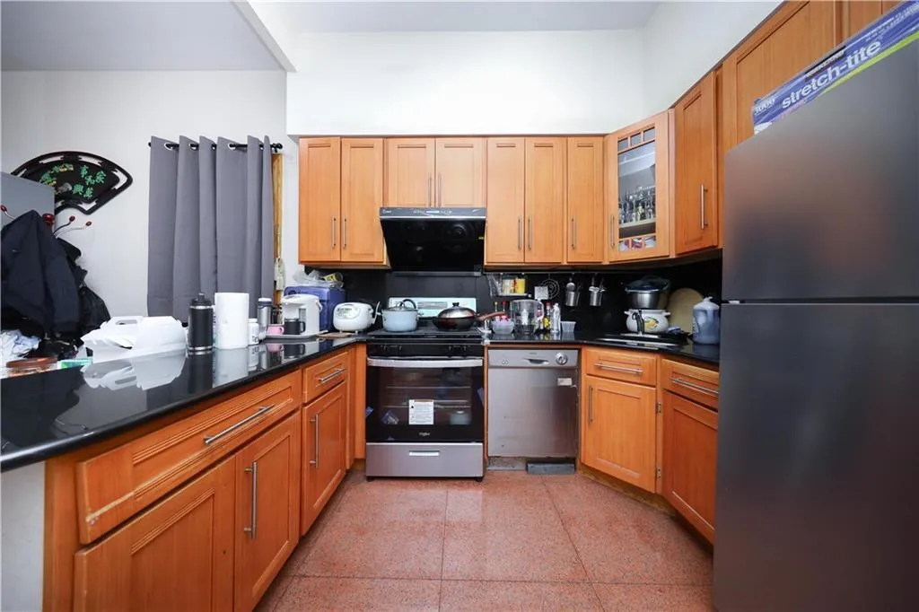 Kitchen with stainless steel appliances, dark countertops, glass insert cabinets, and brown cabinets Kitchen with stainless steel appliances, dark countertops, glass insert cabinets, and brown cabinets