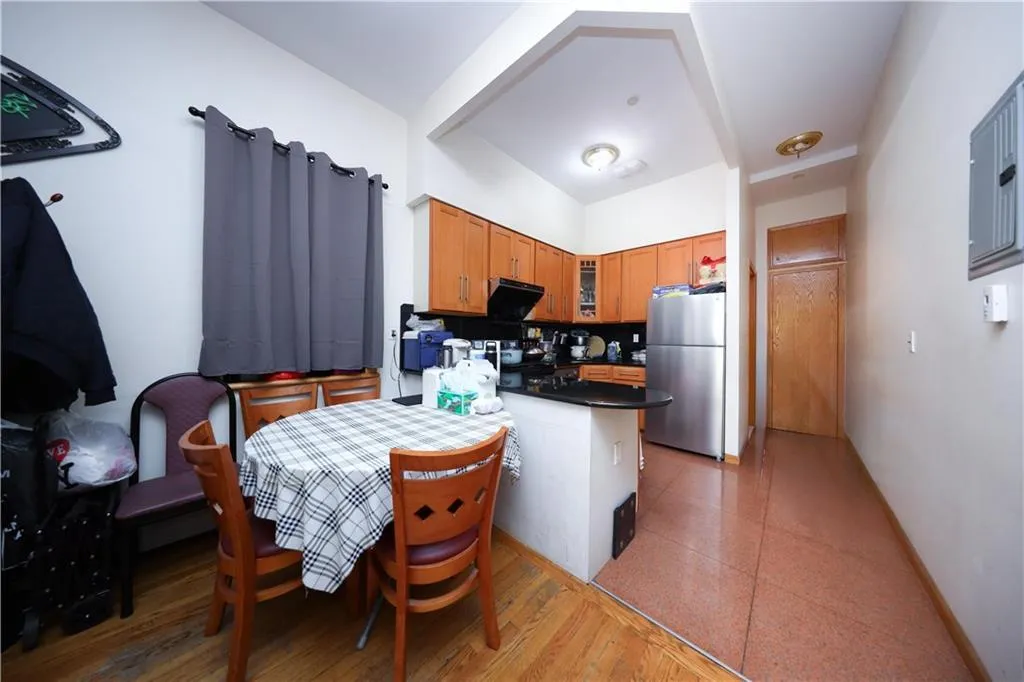 Kitchen featuring freestanding refrigerator, dark countertops, glass insert cabinets, a peninsula, and brown cabinets Kitchen featuring freestanding refrigerator, dark countertops, glass insert cabinets, a peninsula, and brown cabinets