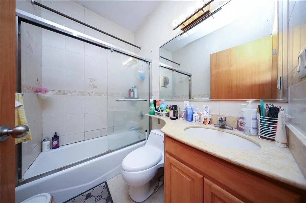 Full bathroom with toilet, vanity, and shower / bath combination with glass door Full bathroom with toilet, vanity, and shower / bath combination with glass door