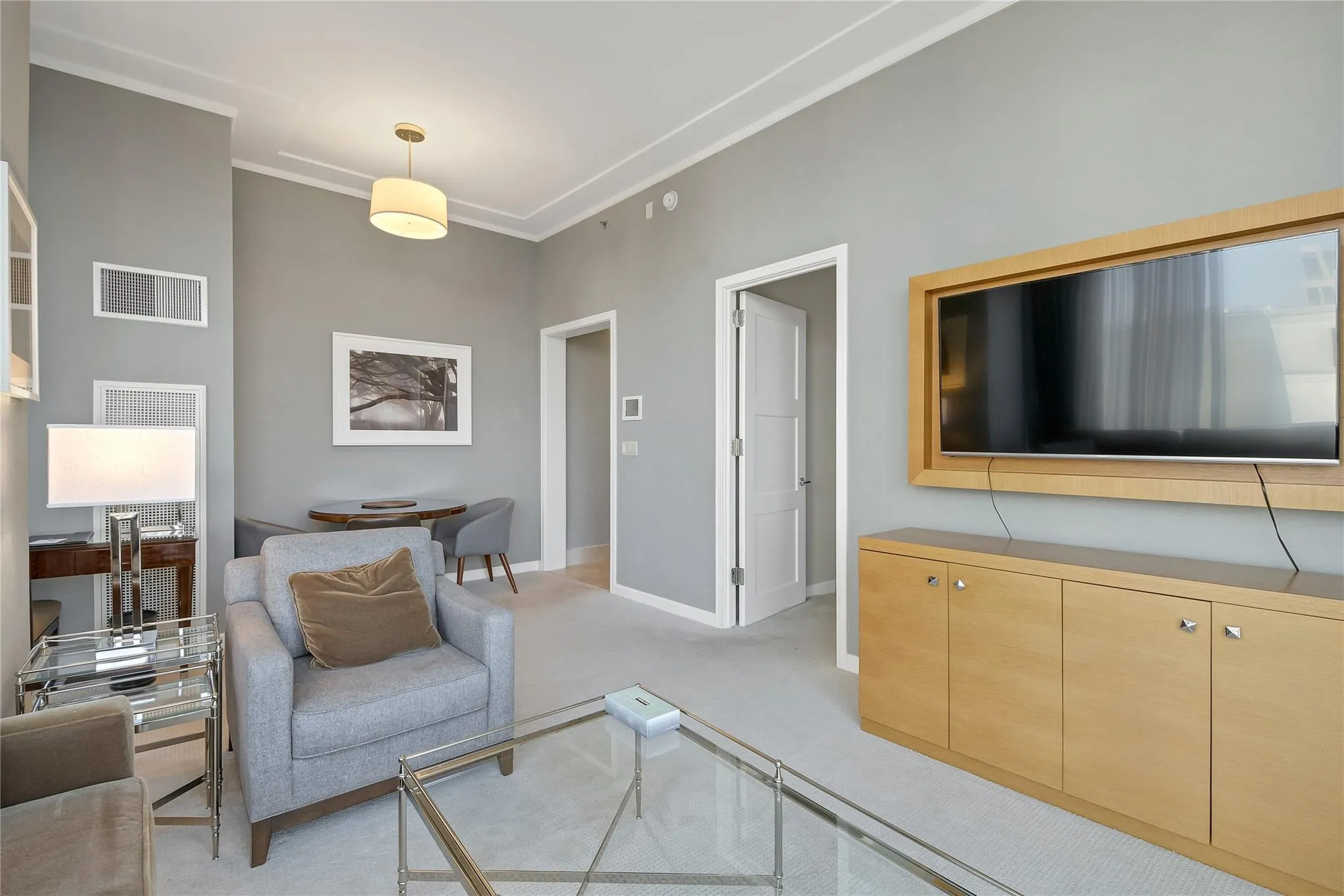 Living area featuring light carpet, baseboards, visible vents, and ornamental molding Living area featuring light carpet, baseboards, visible vents, and ornamental molding