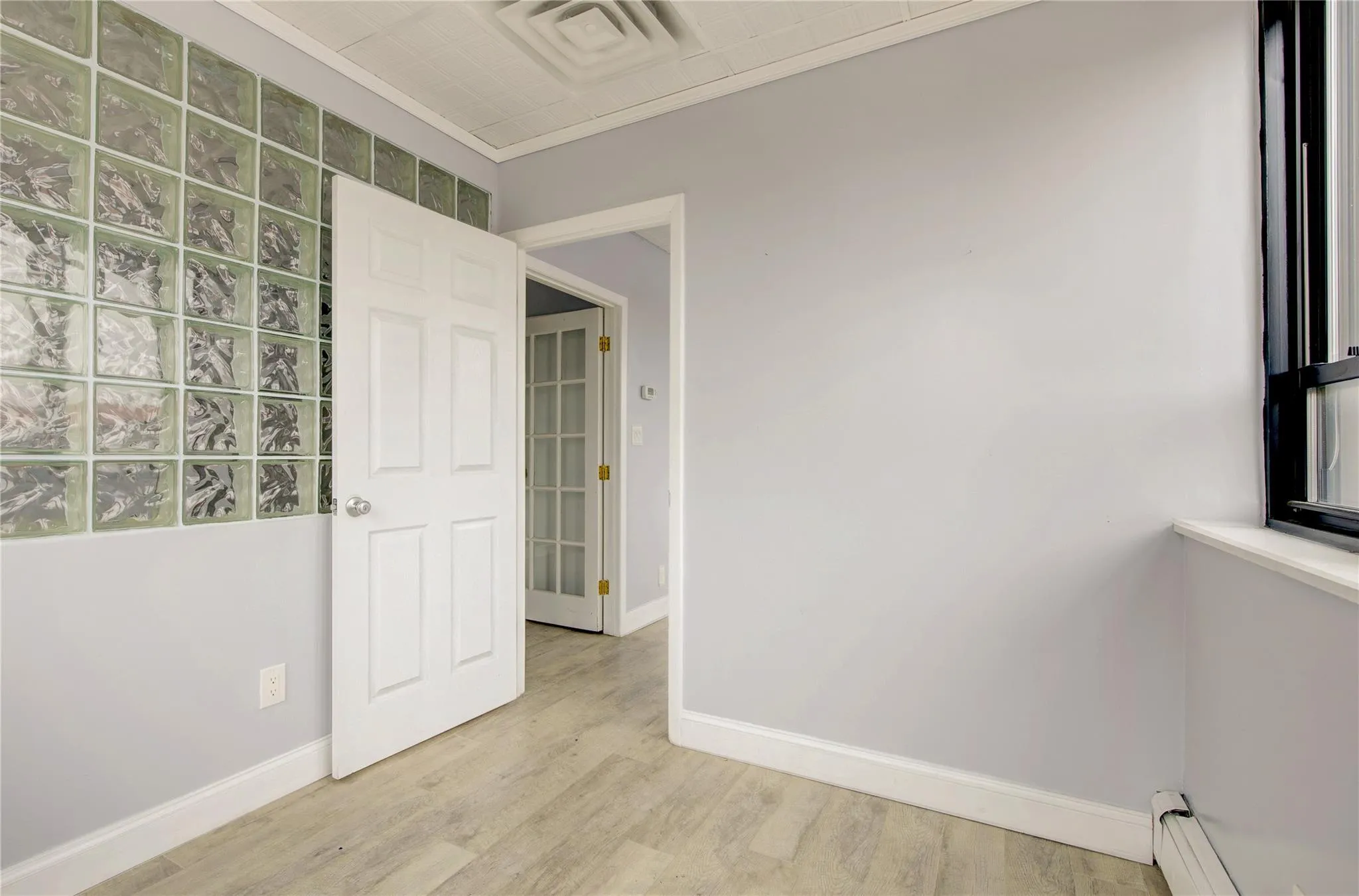 Empty room featuring baseboard heating, baseboards, and light wood-style flooring Empty room featuring baseboard heating, baseboards, and light wood-style flooring
