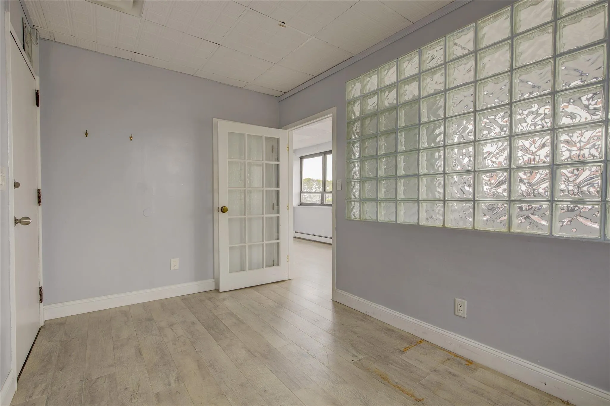 Unfurnished room featuring a baseboard radiator, wood finished floors, baseboards, and french doors Unfurnished room featuring a baseboard radiator, wood finished floors, baseboards, and french doors