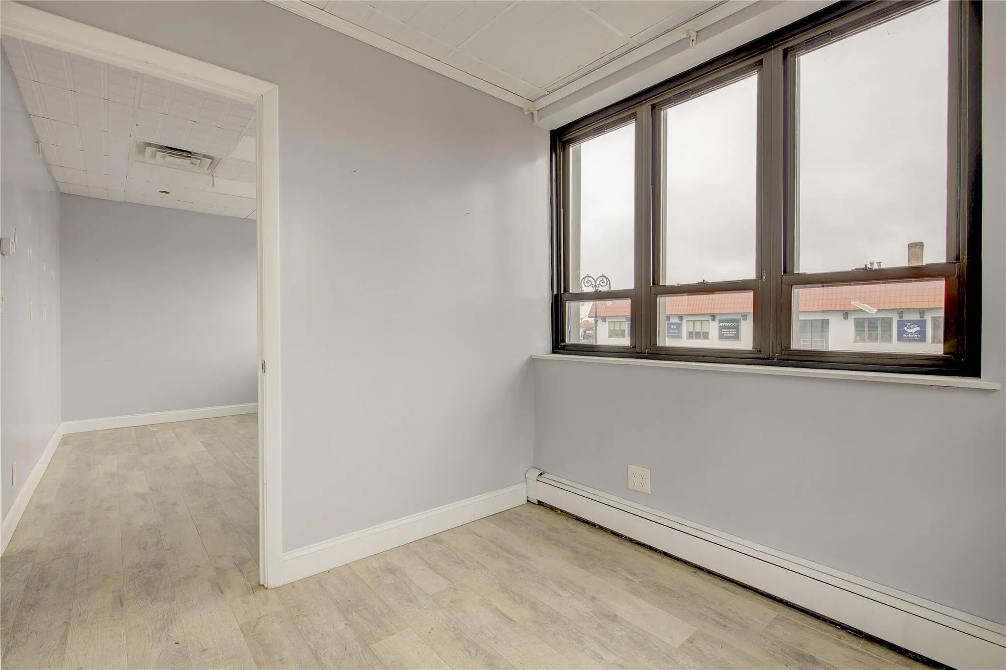 Unfurnished room with a baseboard radiator, wood finished floors, and baseboards Unfurnished room with a baseboard radiator, wood finished floors, and baseboards