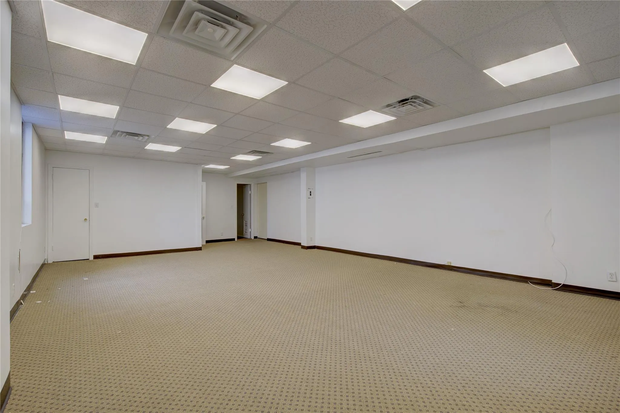 Spare room featuring a drop ceiling, baseboards, and light colored carpet Spare room featuring a drop ceiling, baseboards, and light colored carpet