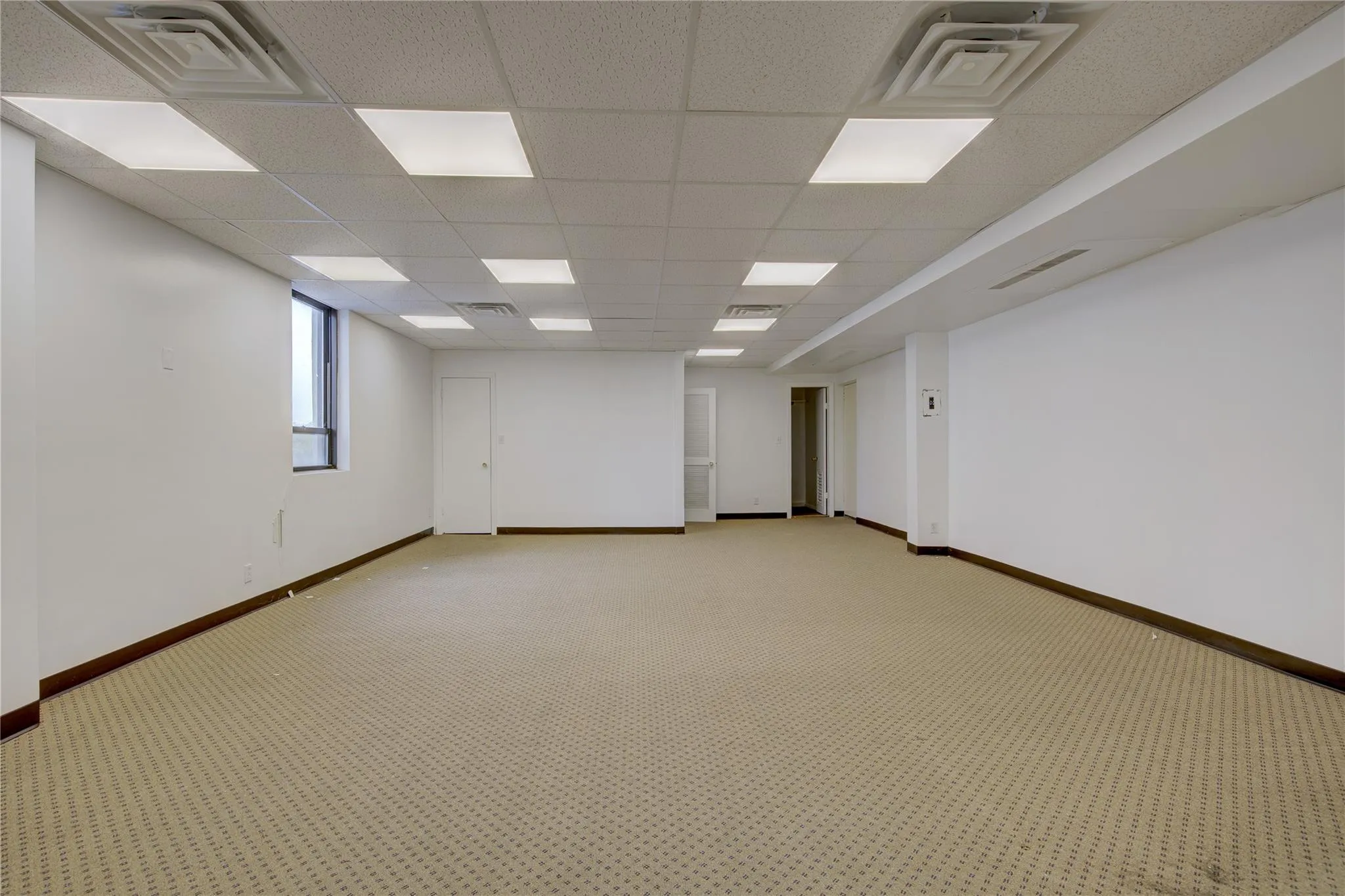 Spare room with baseboards, a paneled ceiling, and light carpet Spare room with baseboards, a paneled ceiling, and light carpet