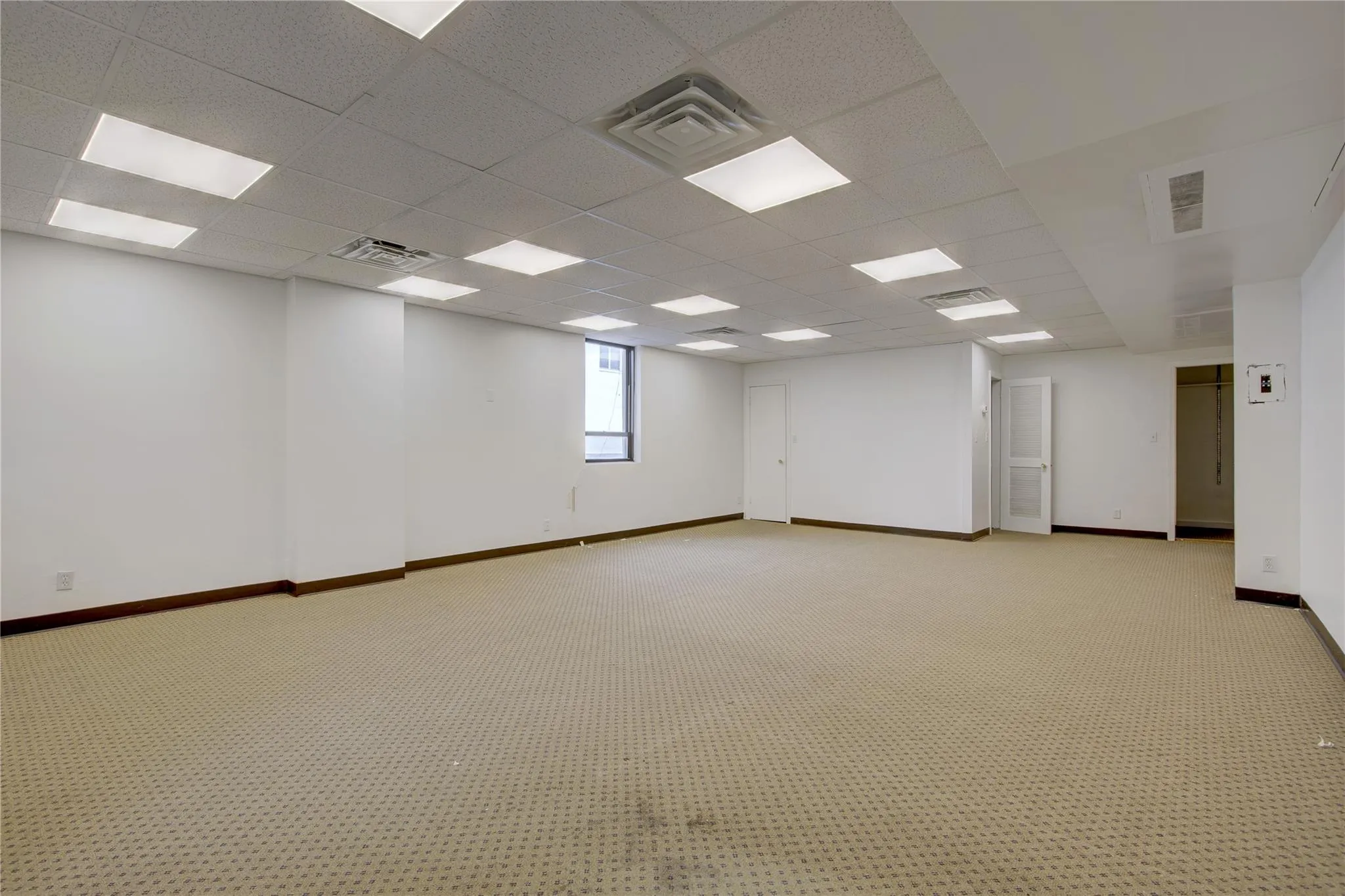 Spare room featuring baseboards, light colored carpet, and a drop ceiling Spare room featuring baseboards, light colored carpet, and a drop ceiling