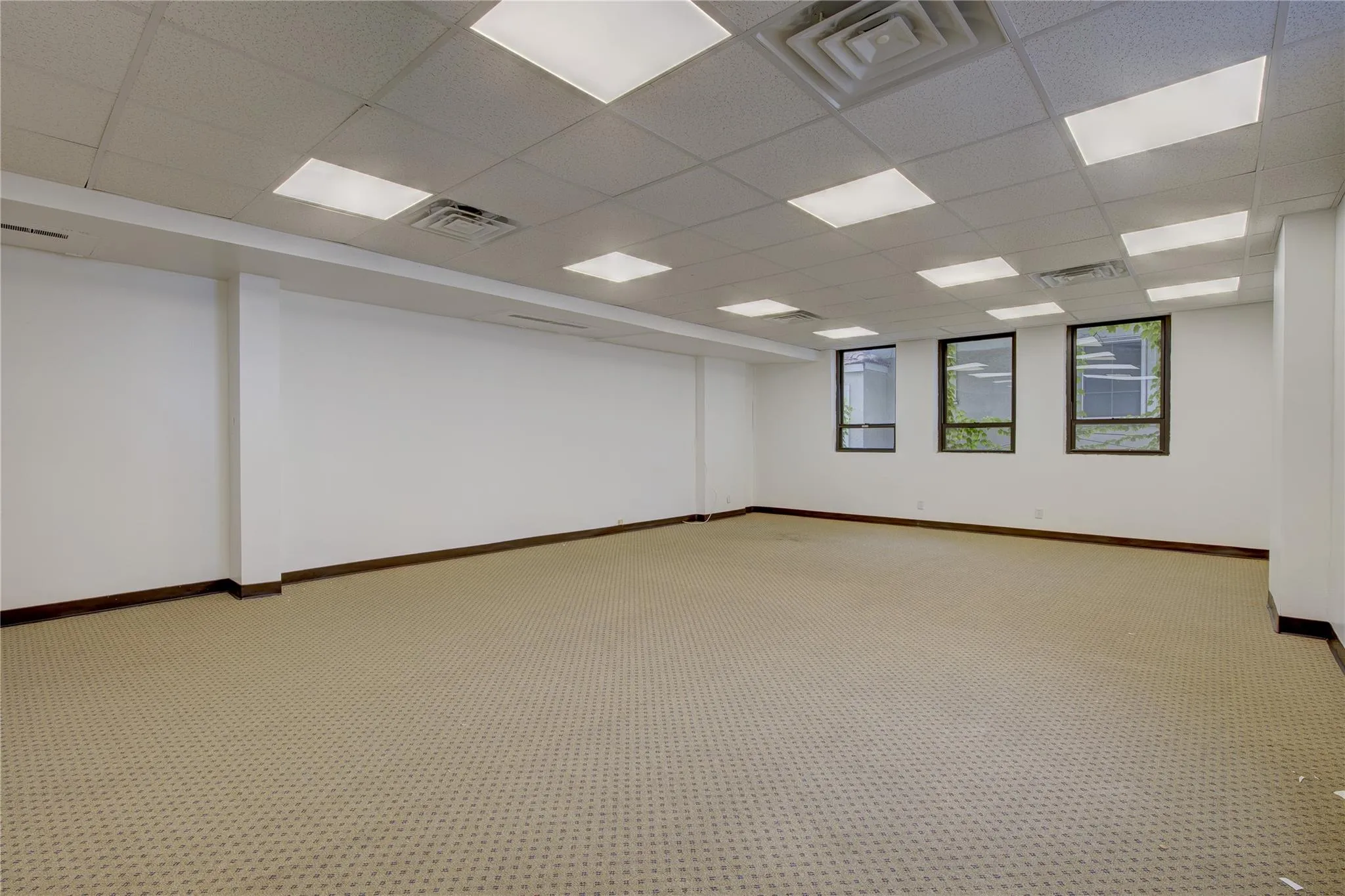 Unfurnished room with a paneled ceiling, baseboards, and carpet flooring Unfurnished room with a paneled ceiling, baseboards, and carpet flooring