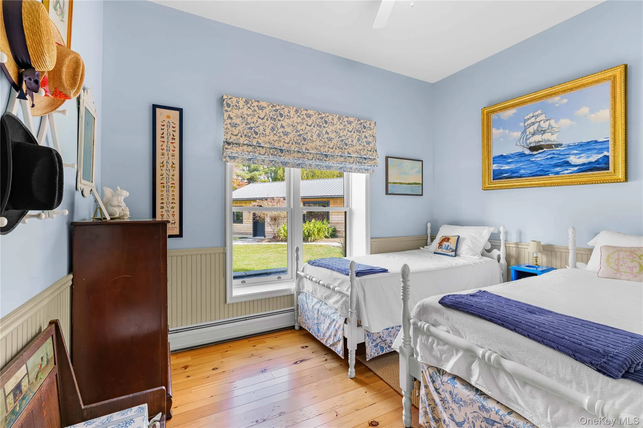 Bedroom featuring baseboard heating, wainscoting, hardwood / wood-style flooring, and ceiling fan Bedroom featuring baseboard heating, wainscoting, hardwood / wood-style flooring, and ceiling fan