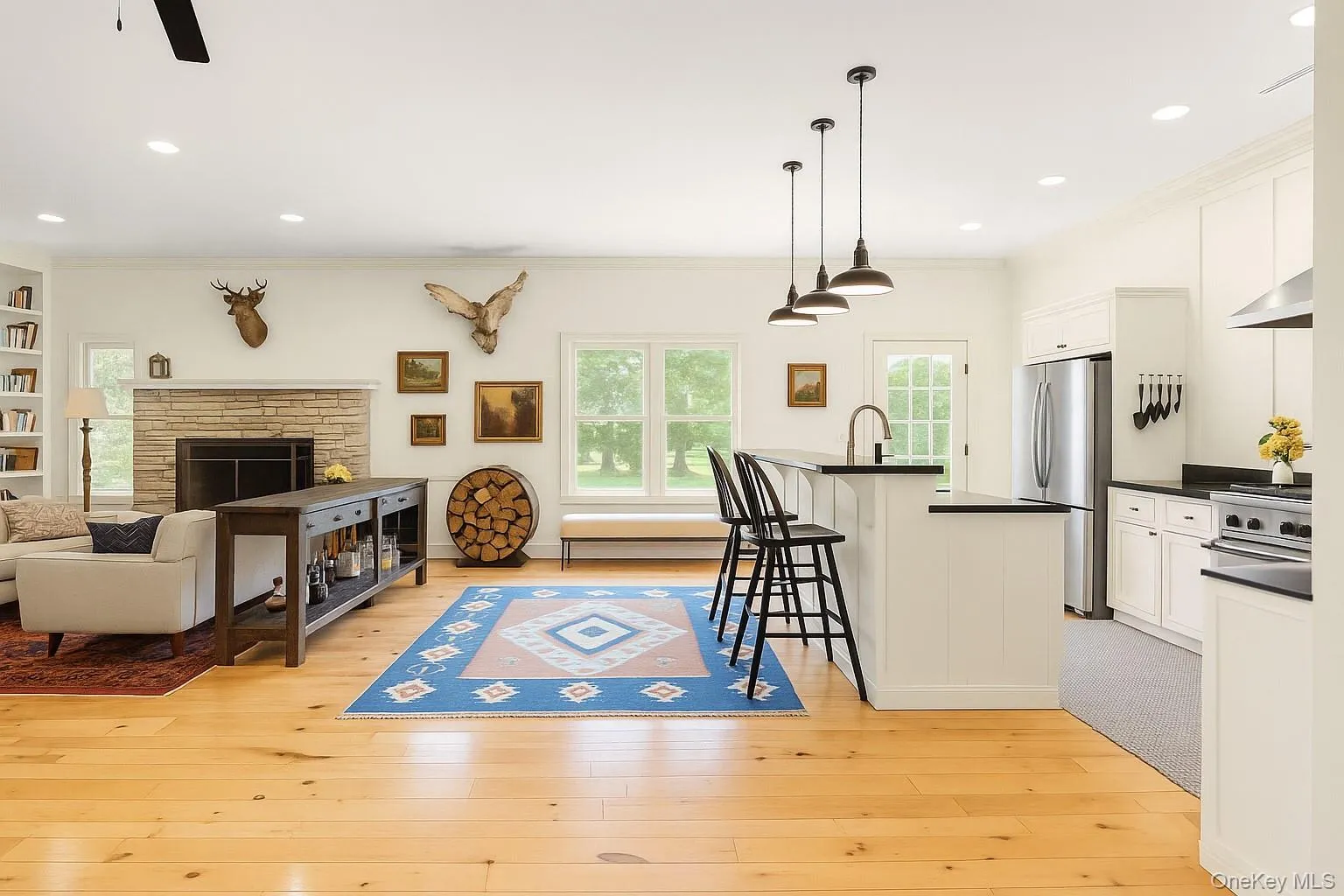 Kitchen with a kitchen breakfast bar, white cabinetry, recessed lighting, stainless steel appliances, and hanging light fixtures Kitchen with a kitchen breakfast bar, white cabinetry, recessed lighting, stainless steel appliances, and hanging light fixtures