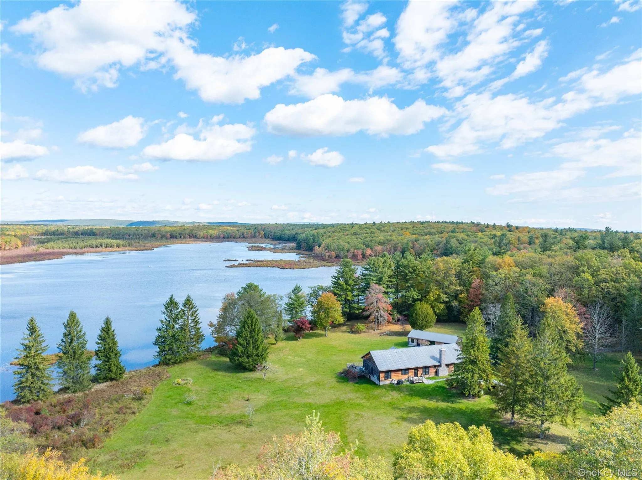 Aerial view of property and surrounding area with a nearby body of water and a heavily wooded area Aerial view of property and surrounding area with a nearby body of water and a heavily wooded area