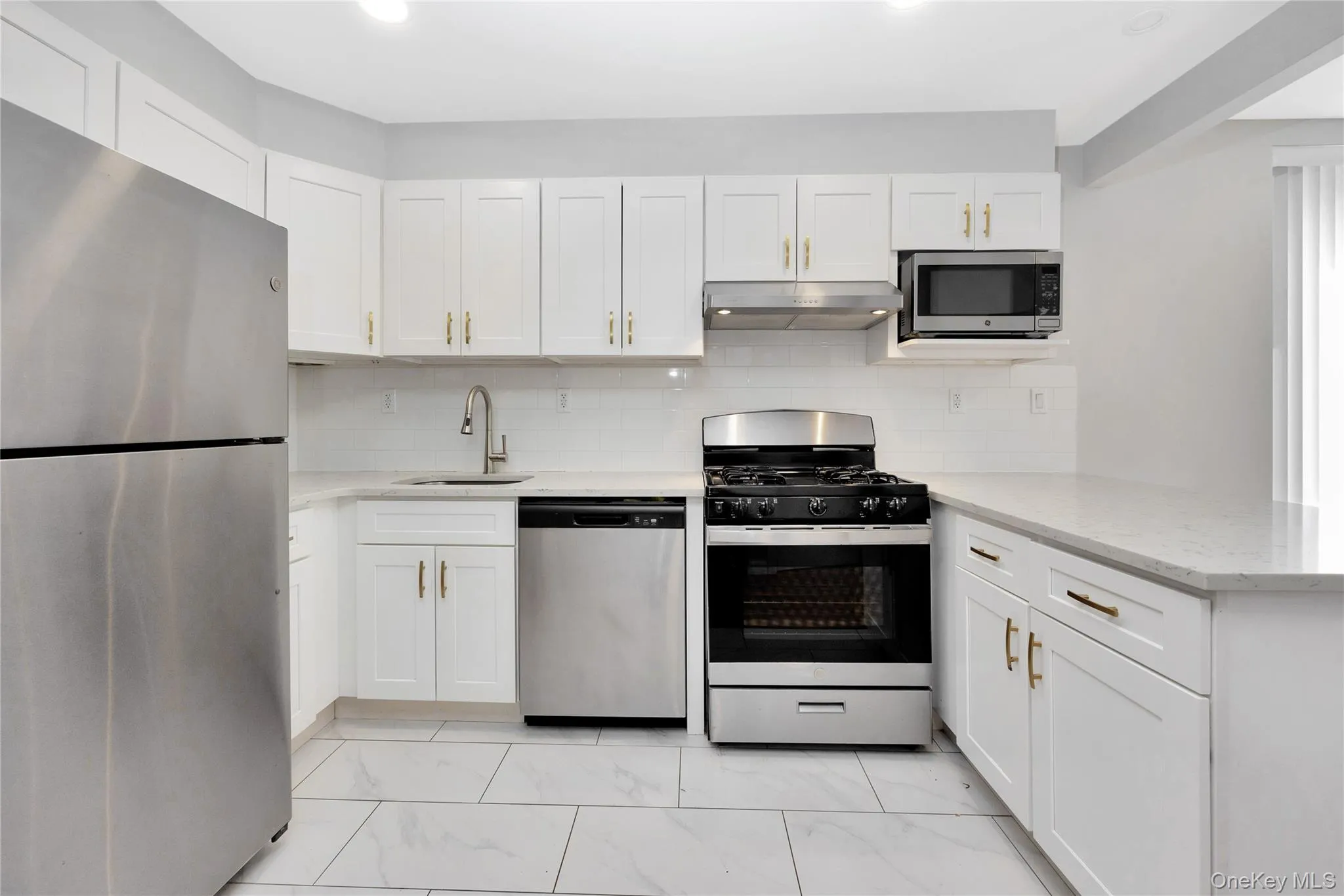 Kitchen with a peninsula, under cabinet range hood, stainless steel appliances, marble finish floor, and a sink Kitchen with a peninsula, under cabinet range hood, stainless steel appliances, marble finish floor, and a sink