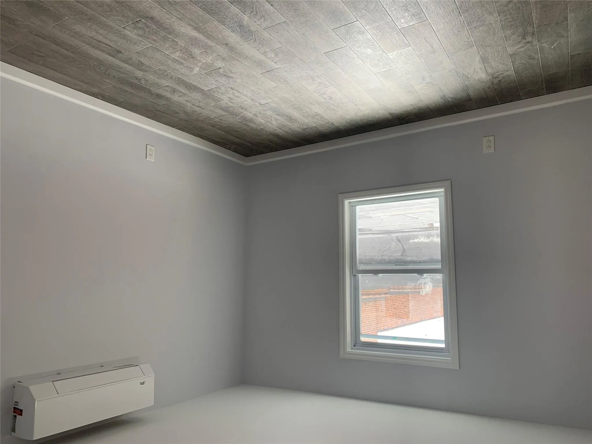 Unfurnished room with a wall mounted AC, dark wood-style floors, and baseboards Unfurnished room with a wall mounted AC, dark wood-style floors, and baseboards