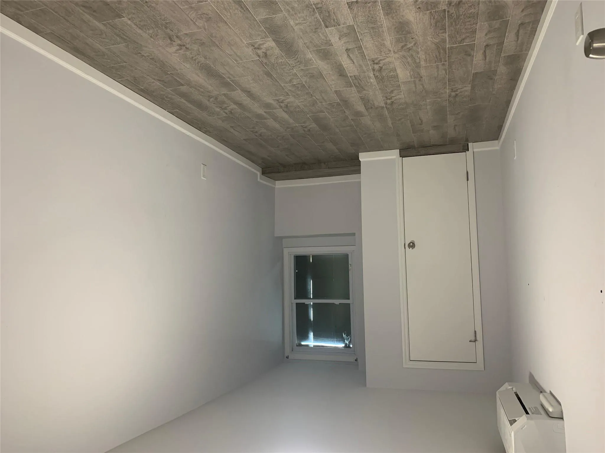 Unfurnished room with a wall unit AC, dark wood-style floors, and baseboards Unfurnished room with a wall unit AC, dark wood-style floors, and baseboards