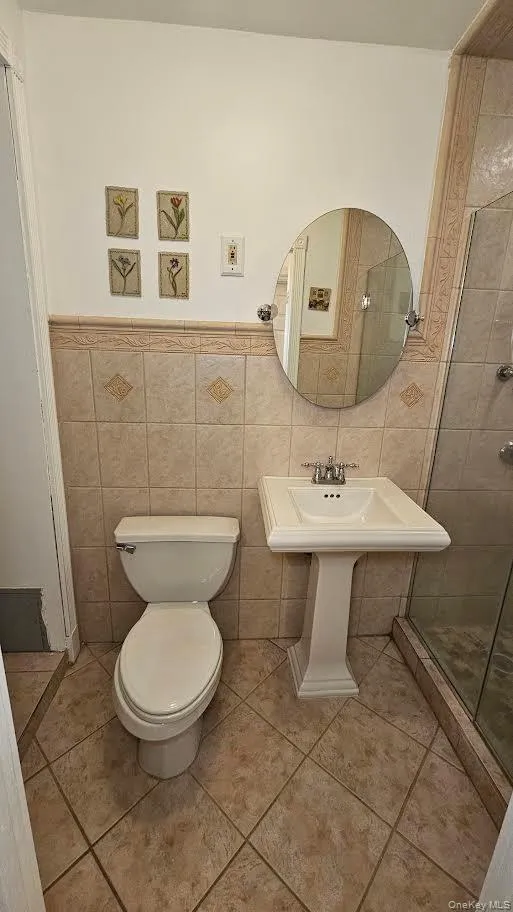 Full bath with tile walls, toilet, a stall shower, tile patterned flooring. Full bath with tile walls, toilet, a stall shower, tile patterned flooring.