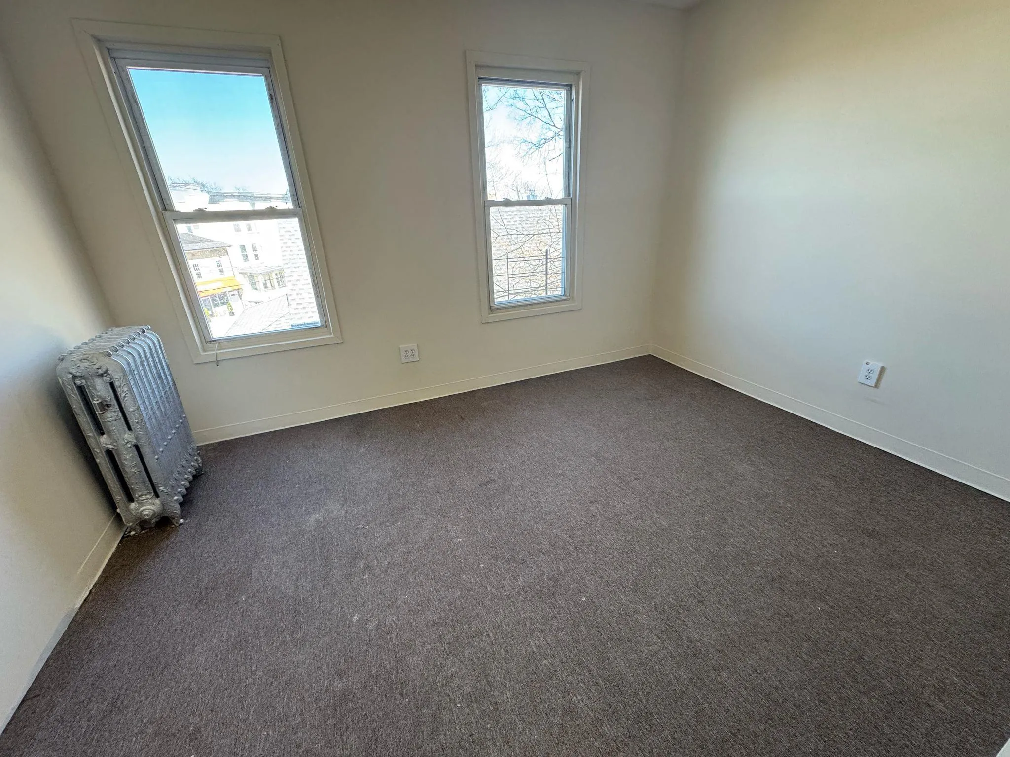 Unfurnished room featuring dark carpet and baseboards Unfurnished room featuring dark carpet and baseboards
