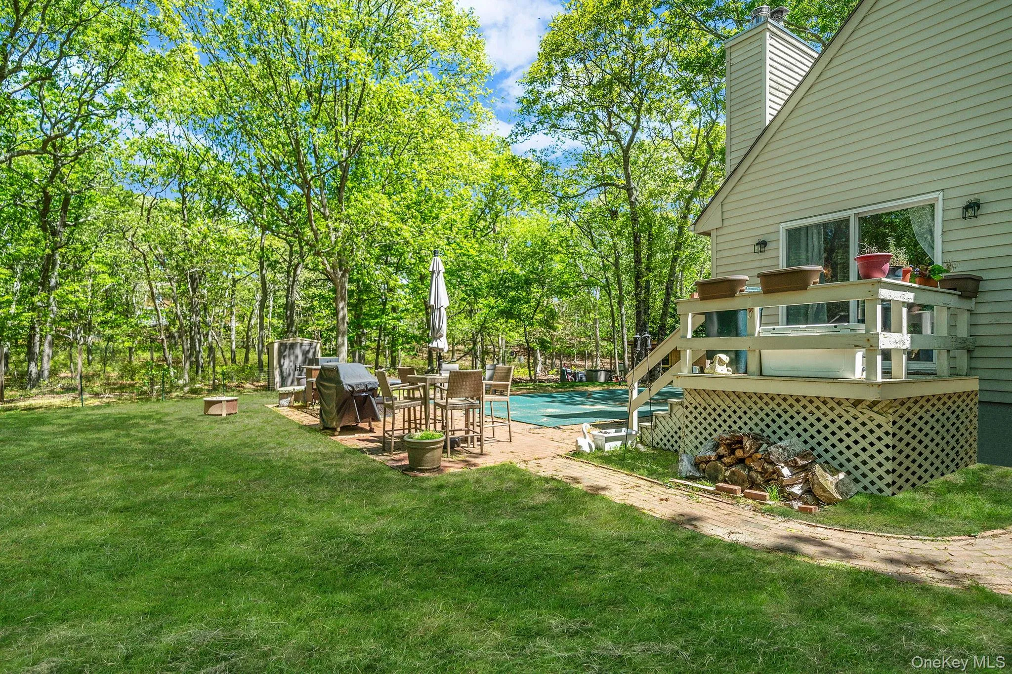 View of grassy yard with a wooden deck and a covered pool View of grassy yard with a wooden deck and a covered pool