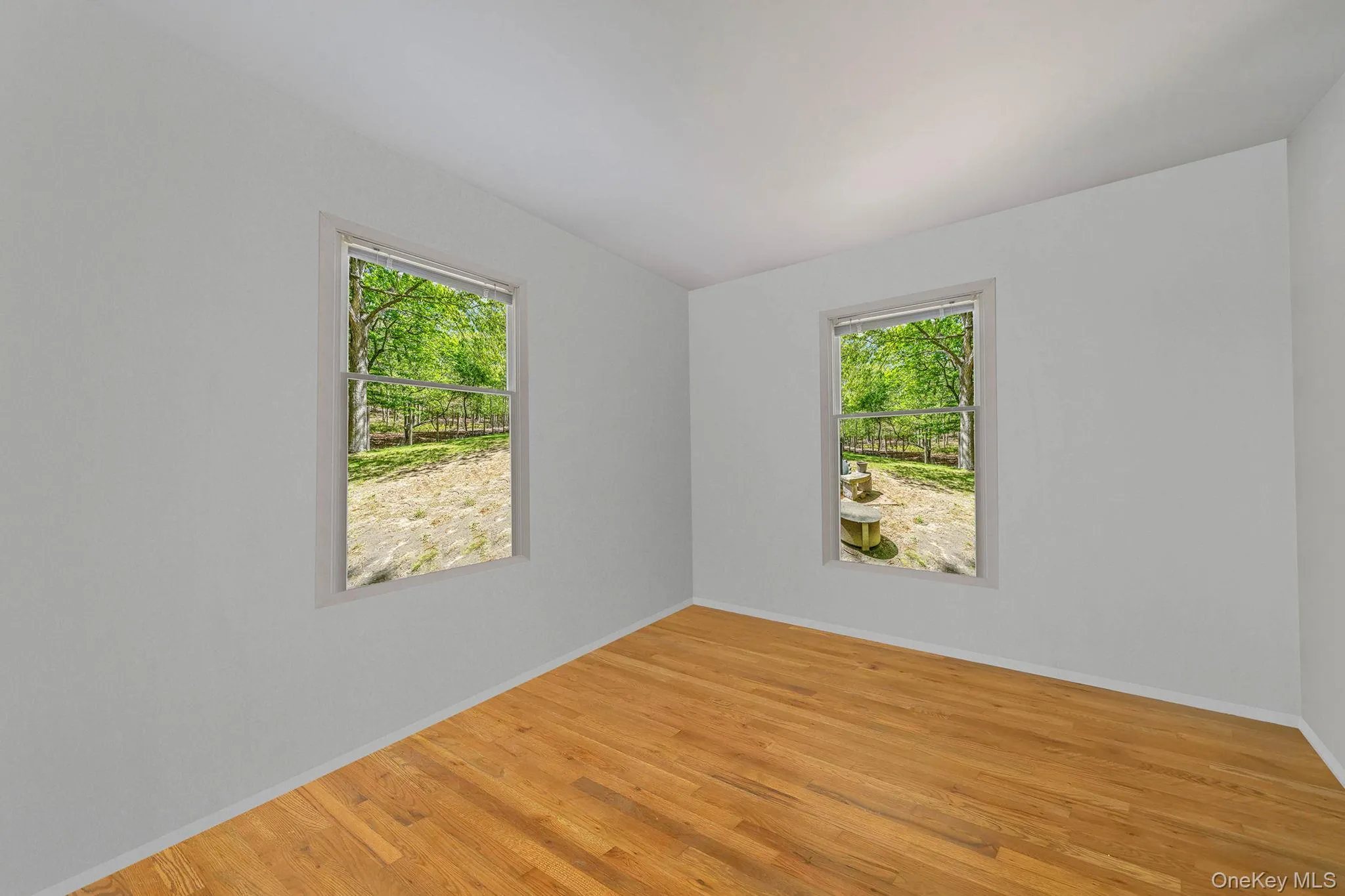 Empty room with healthy amount of natural light, light wood-type flooring, and baseboards Empty room with healthy amount of natural light, light wood-type flooring, and baseboards