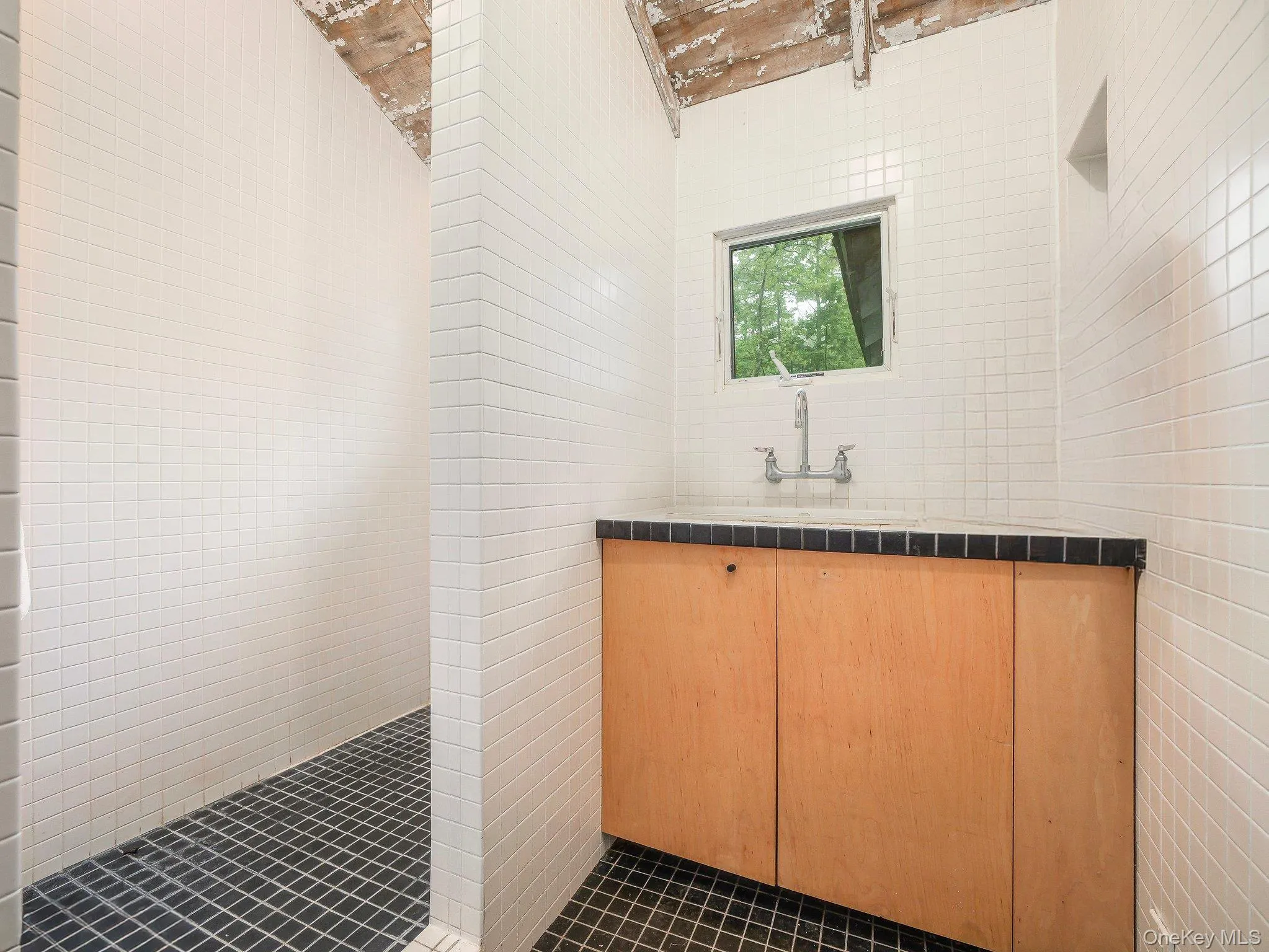 Full bath featuring tile walls, tile patterned flooring, vanity, and tiled shower Full bath featuring tile walls, tile patterned flooring, vanity, and tiled shower