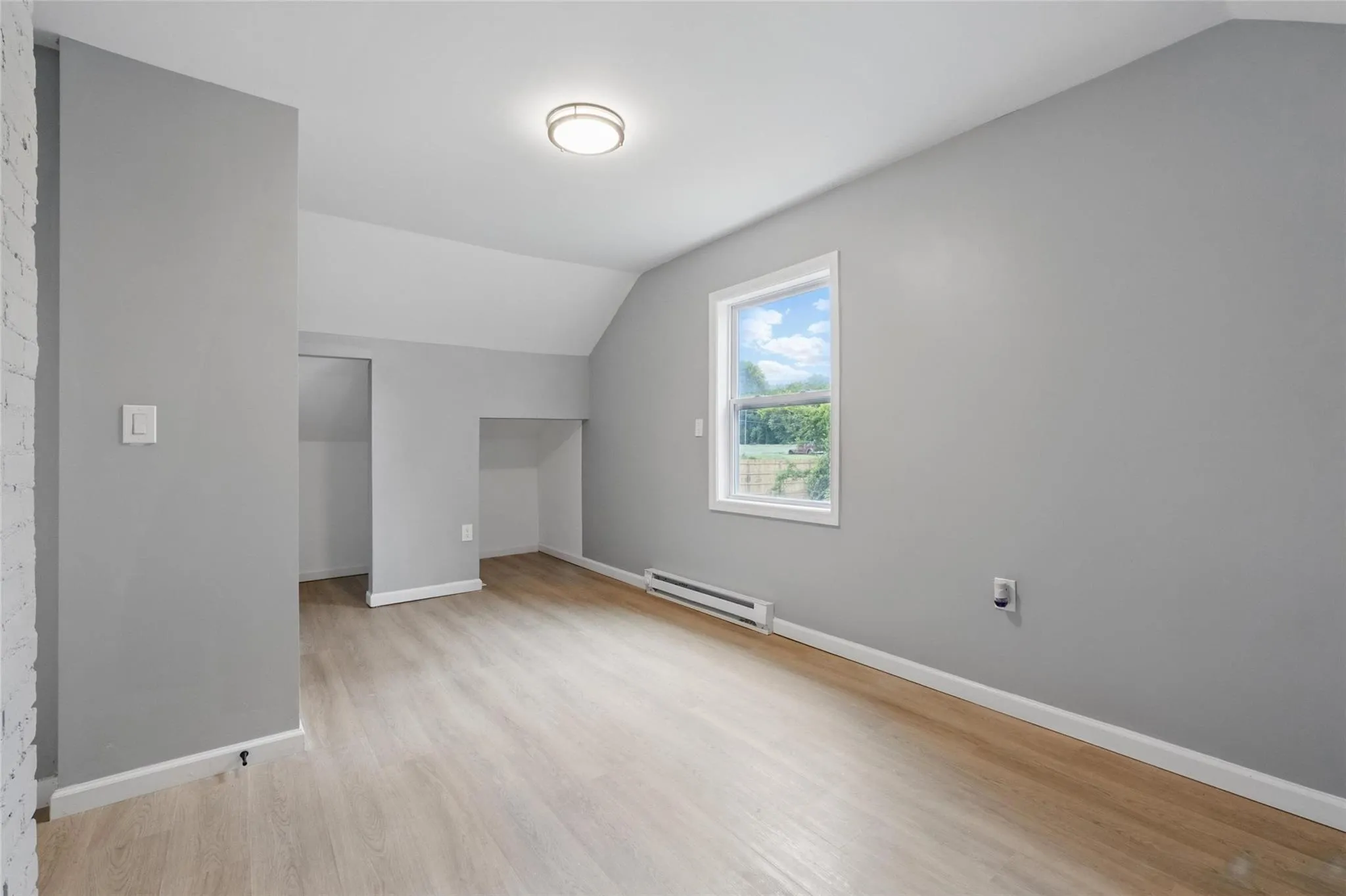 Bonus room featuring lofted ceiling, a baseboard radiator, light wood finished floors, and baseboards Bonus room featuring lofted ceiling, a baseboard radiator, light wood finished floors, and baseboards