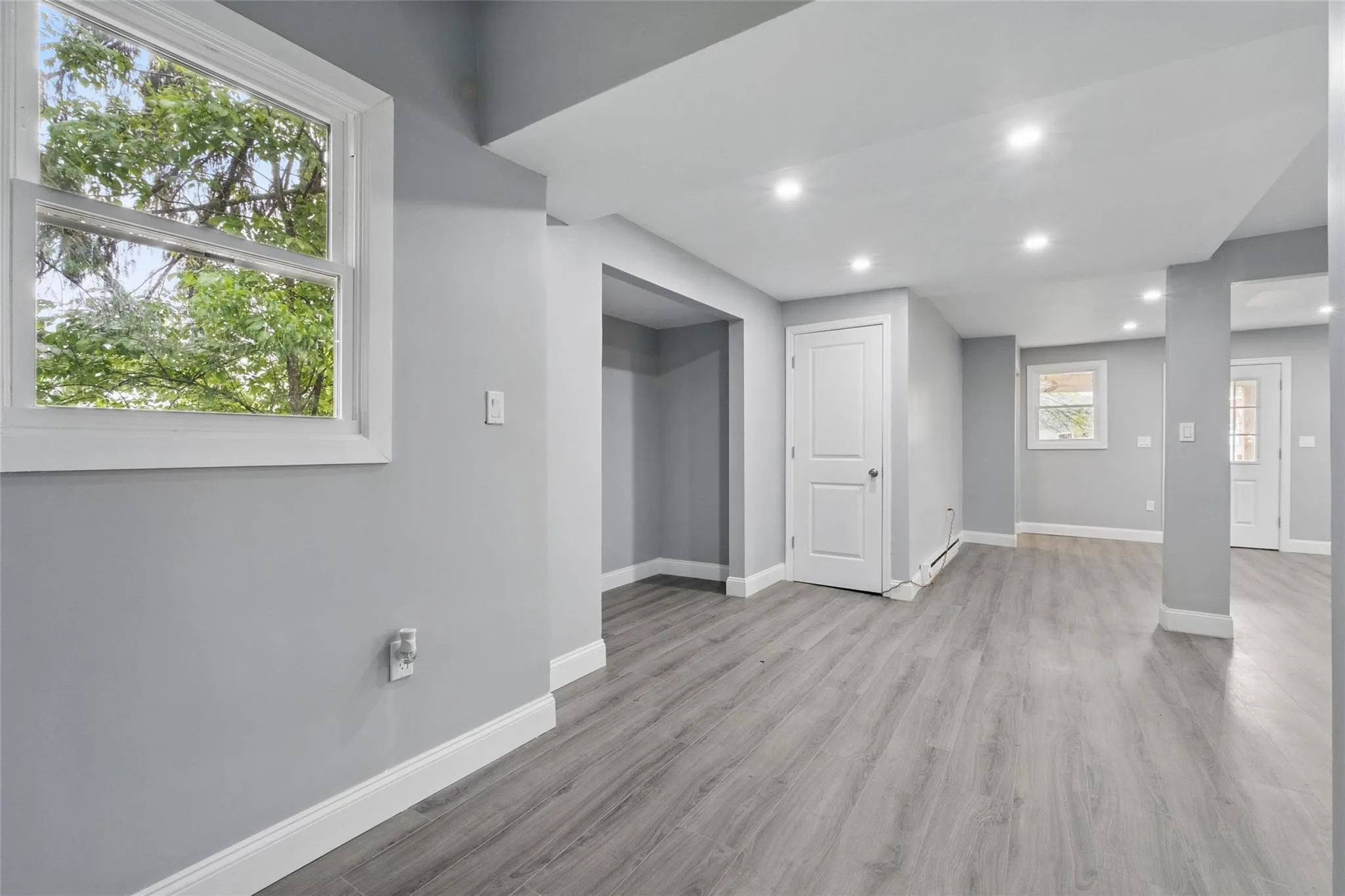 Empty room with baseboards, recessed lighting, light wood-type flooring, and a baseboard heating unit Empty room with baseboards, recessed lighting, light wood-type flooring, and a baseboard heating unit