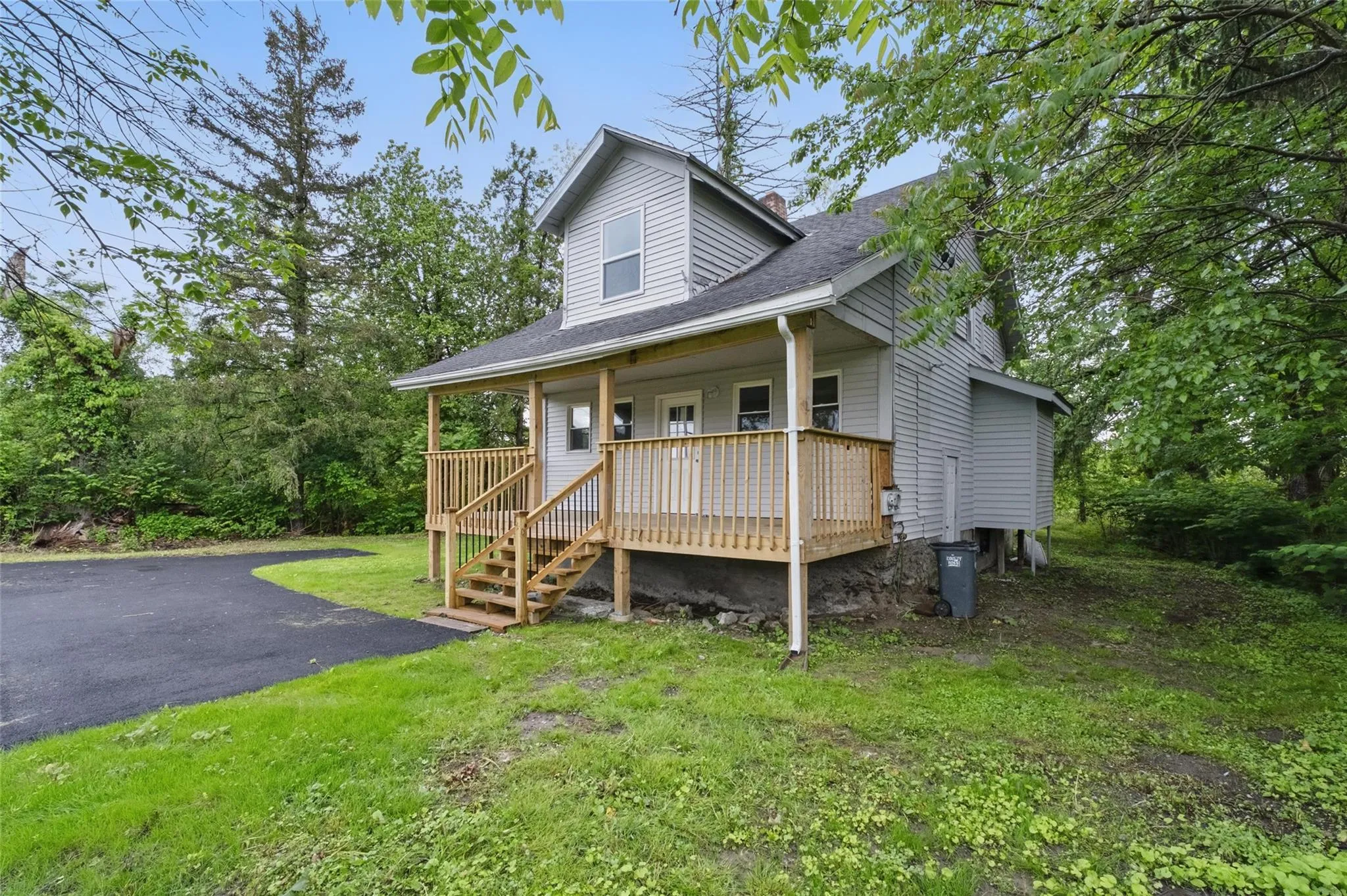 View of front of property with covered porch, a front yard, and a shingled roof View of front of property with covered porch, a front yard, and a shingled roof