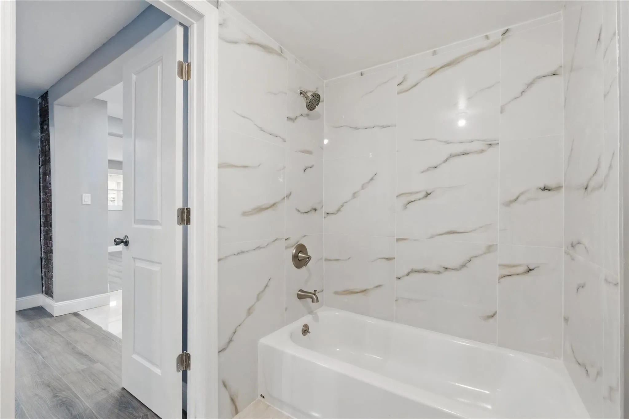 Full bathroom featuring shower combination and wood finished floors Full bathroom featuring shower combination and wood finished floors