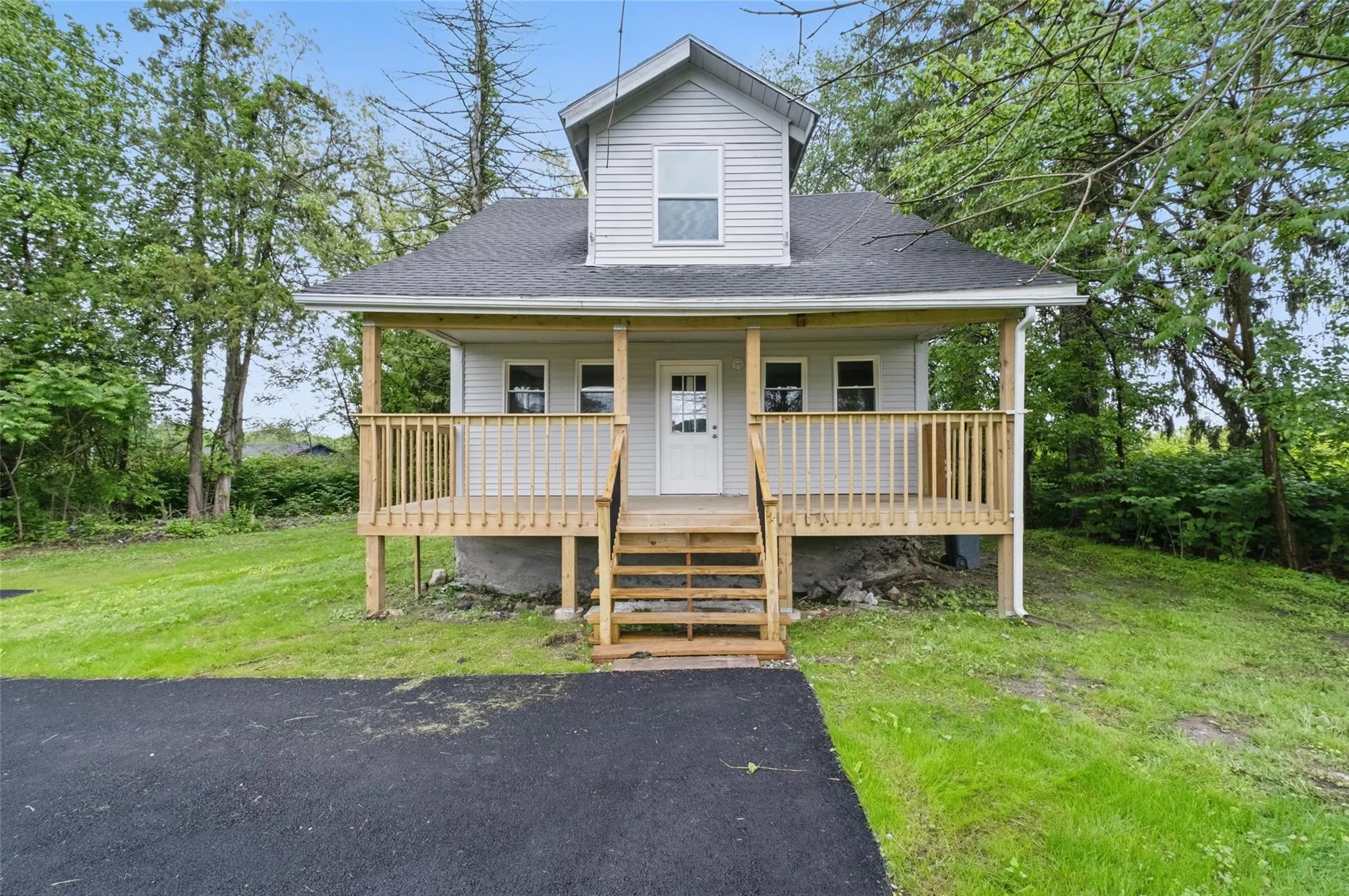 View of front of property with covered porch, a front yard, and a shingled roof View of front of property with covered porch, a front yard, and a shingled roof