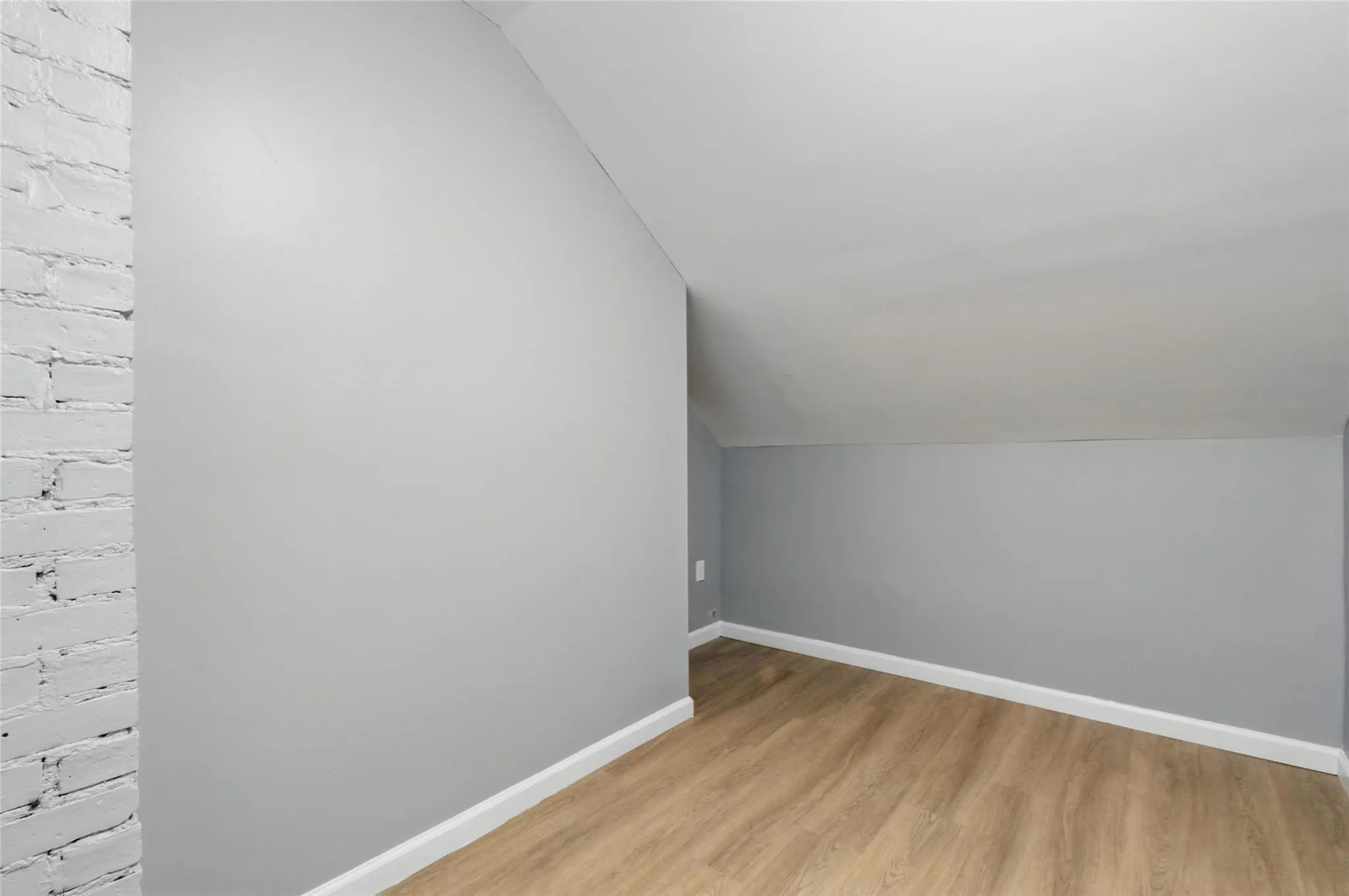 Bonus room with vaulted ceiling, light wood-style floors, and baseboards Bonus room with vaulted ceiling, light wood-style floors, and baseboards
