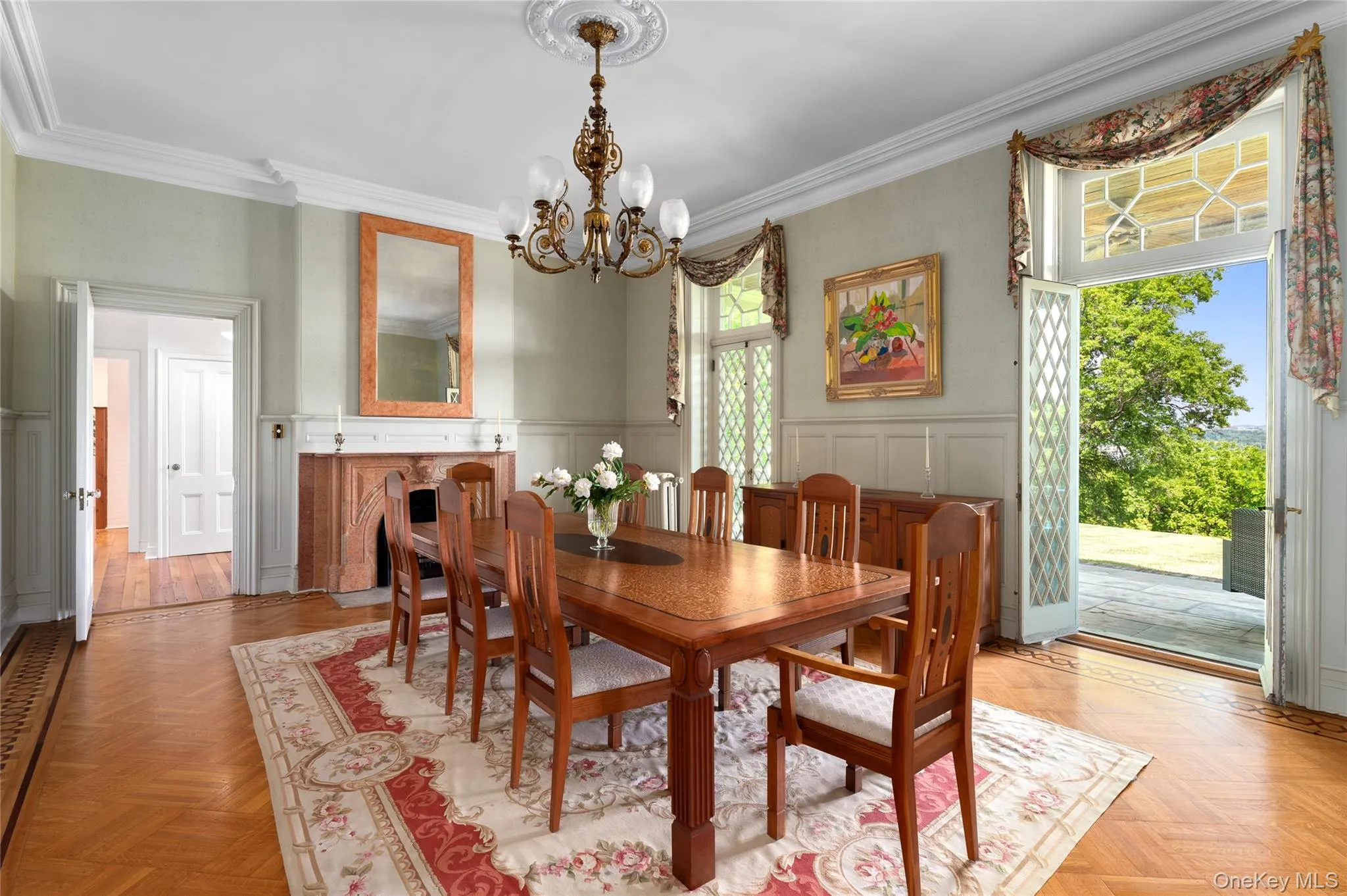 Marble fireplace, diamond-patterned glass doors with veranda access, hand-painted walls, wainscoting, crown molding, gasolier-style chandelier. Marble fireplace, diamond-patterned glass doors with veranda access, hand-painted walls, wainscoting, crown molding, gasolier-style chandelier.