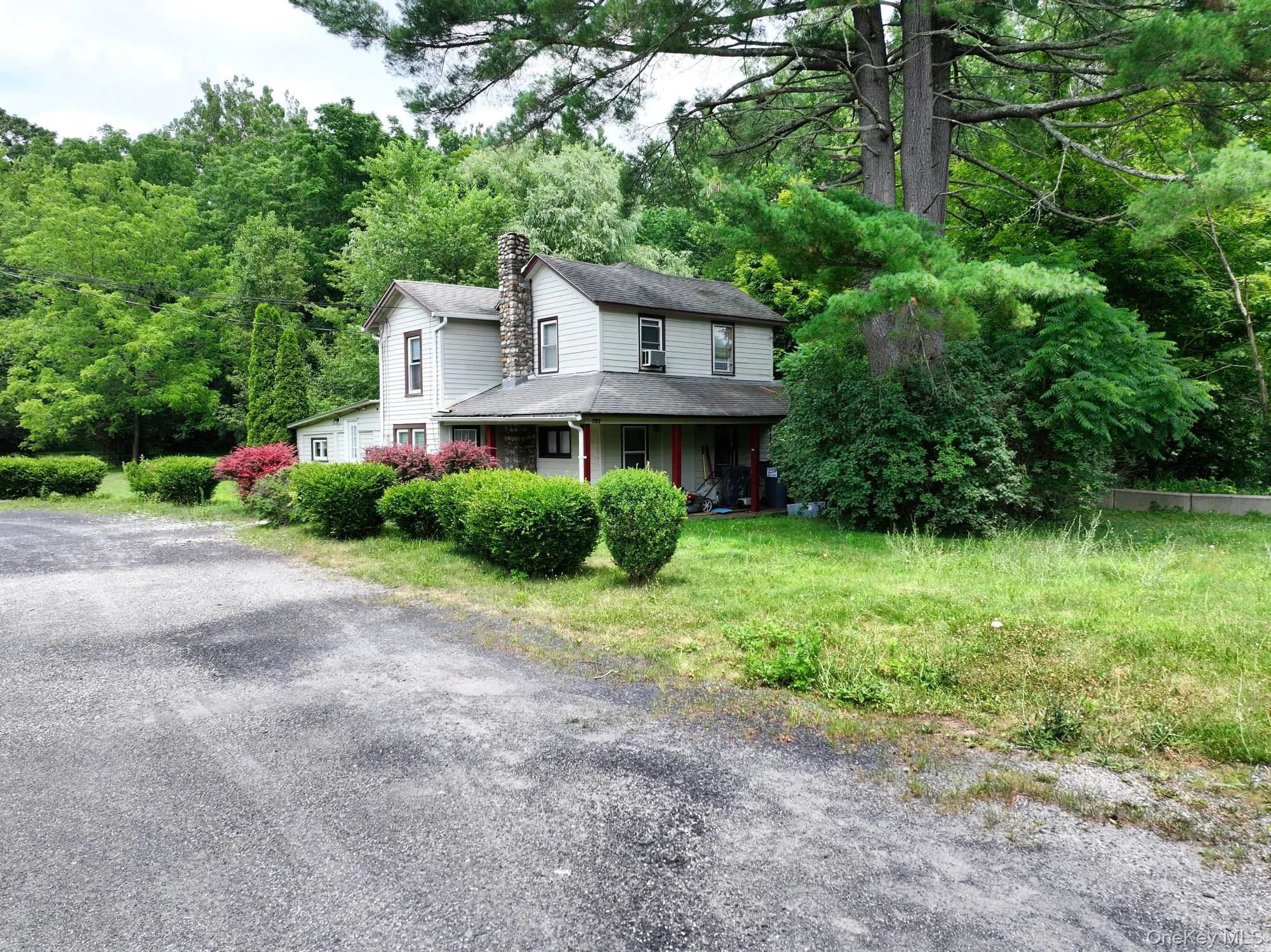 View of front of property featuring a chimney, a shingled roof, and a wooded view View of front of property featuring a chimney, a shingled roof, and a wooded view