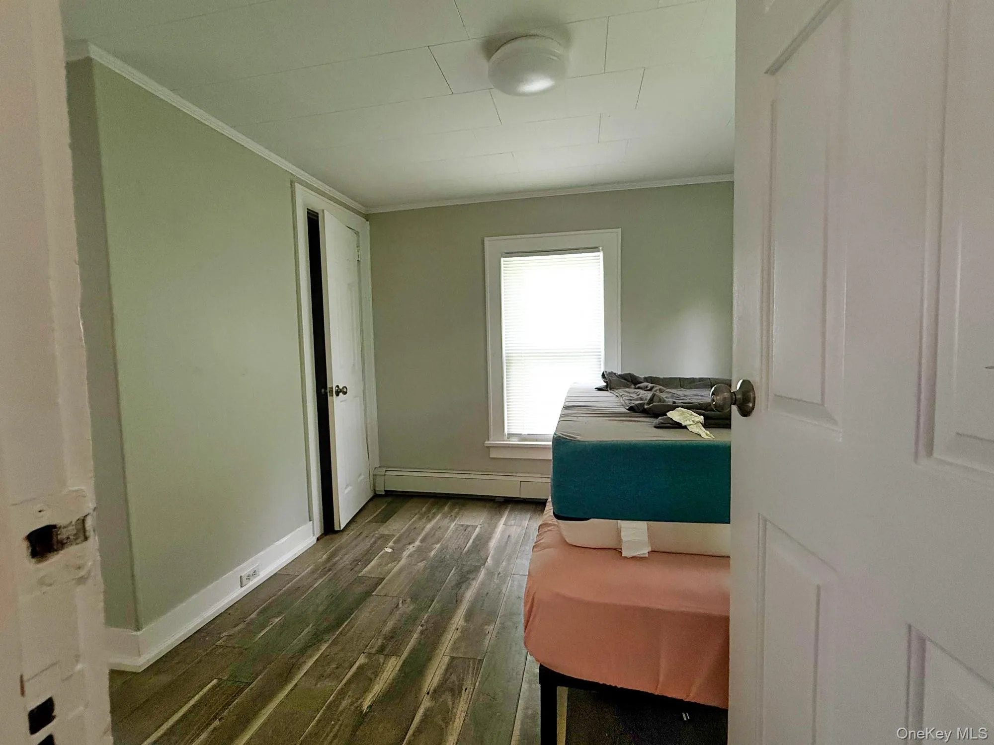 Hallway with a baseboard radiator, dark wood-type flooring, and ornamental molding Hallway with a baseboard radiator, dark wood-type flooring, and ornamental molding