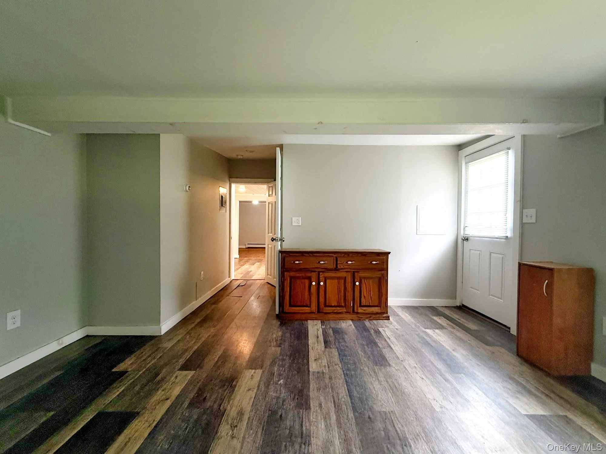 Spare room with dark wood-type flooring and baseboards Spare room with dark wood-type flooring and baseboards